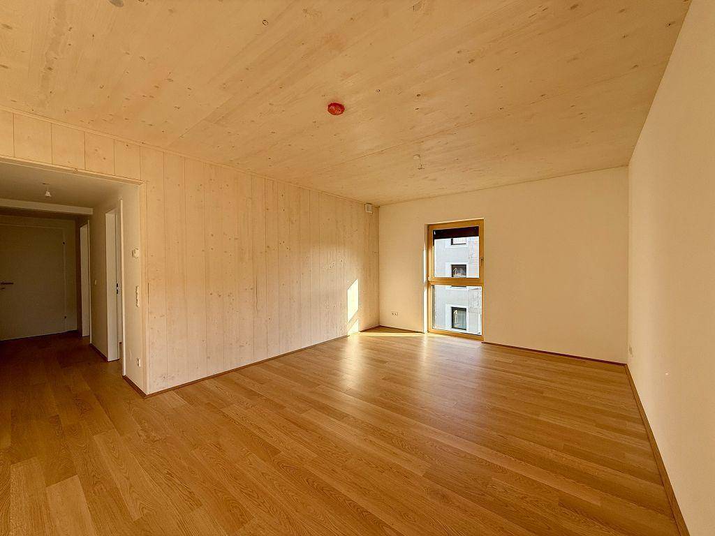 Leerer Raum mit Holzboden und einer Holzwand, die eine warme Atmosphäre schafft.