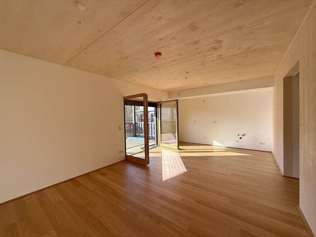 Geräumiges, sonniges Zimmer mit Holzboden und Holzbalkendecke, bereit zur Einrichtung.