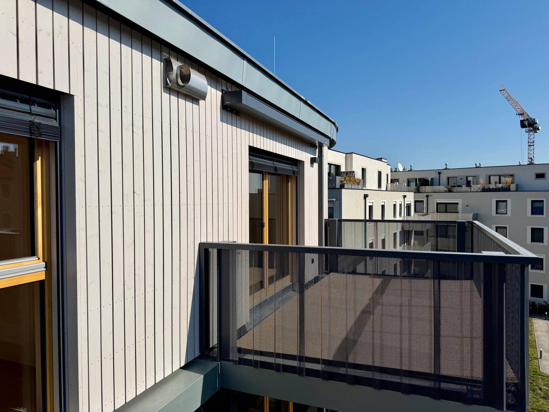 Balkon mit Holzfassade und Blick auf die Nachbarschaft und einen Baukran.