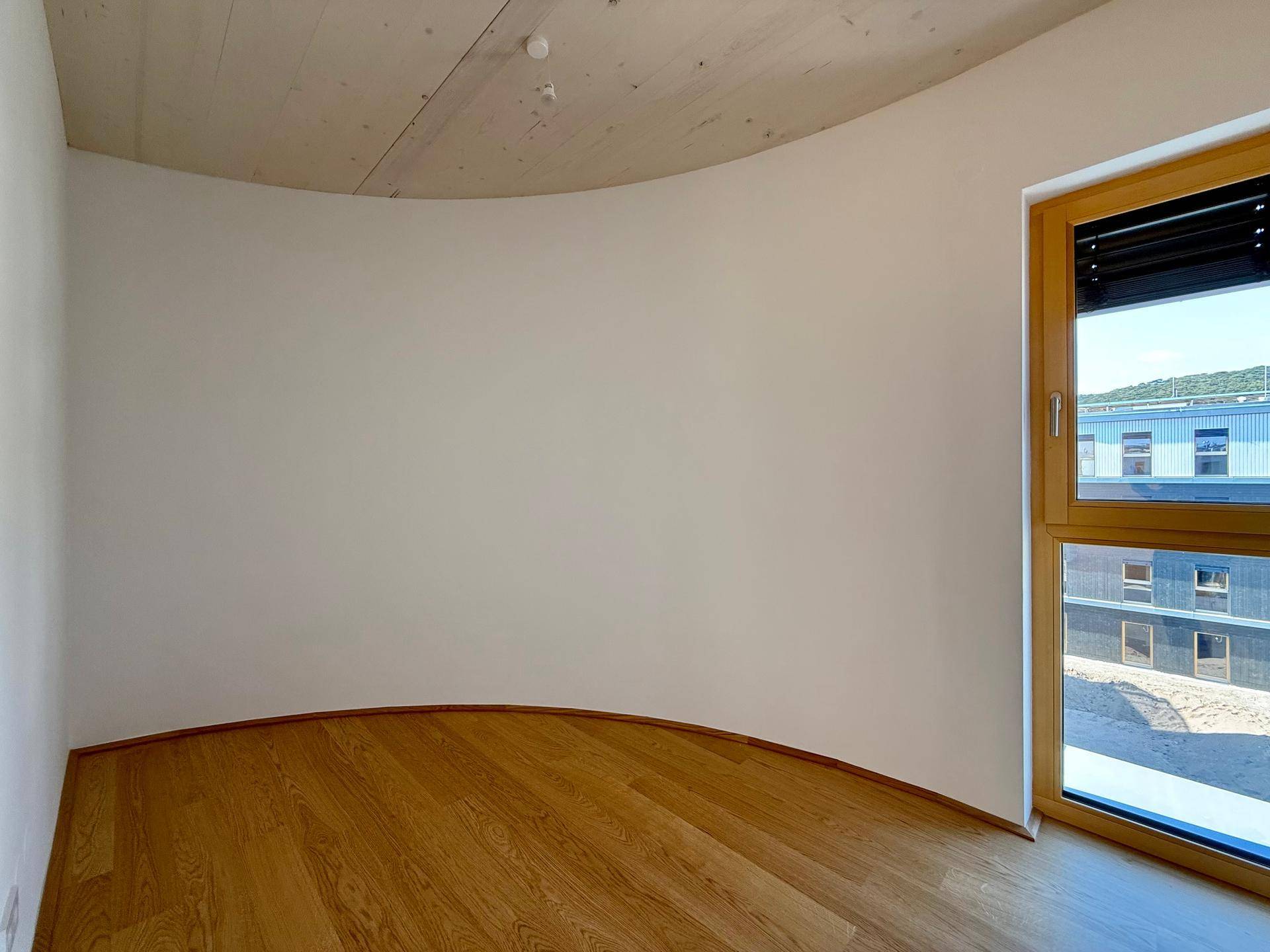 Modernes Zimmer mit Holzboden und einer eleganten Rundung in der Wandgestaltung.