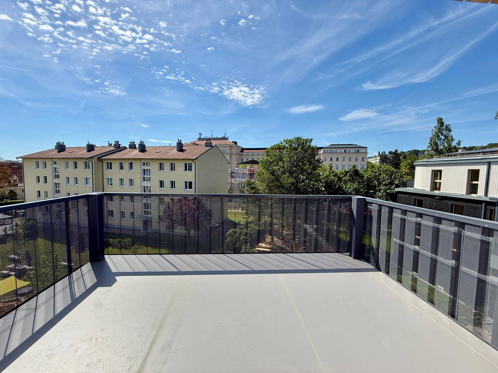 Weitläufiger Balkon mit Panoramablick über die Stadt und grüne Hügel am Horizont.