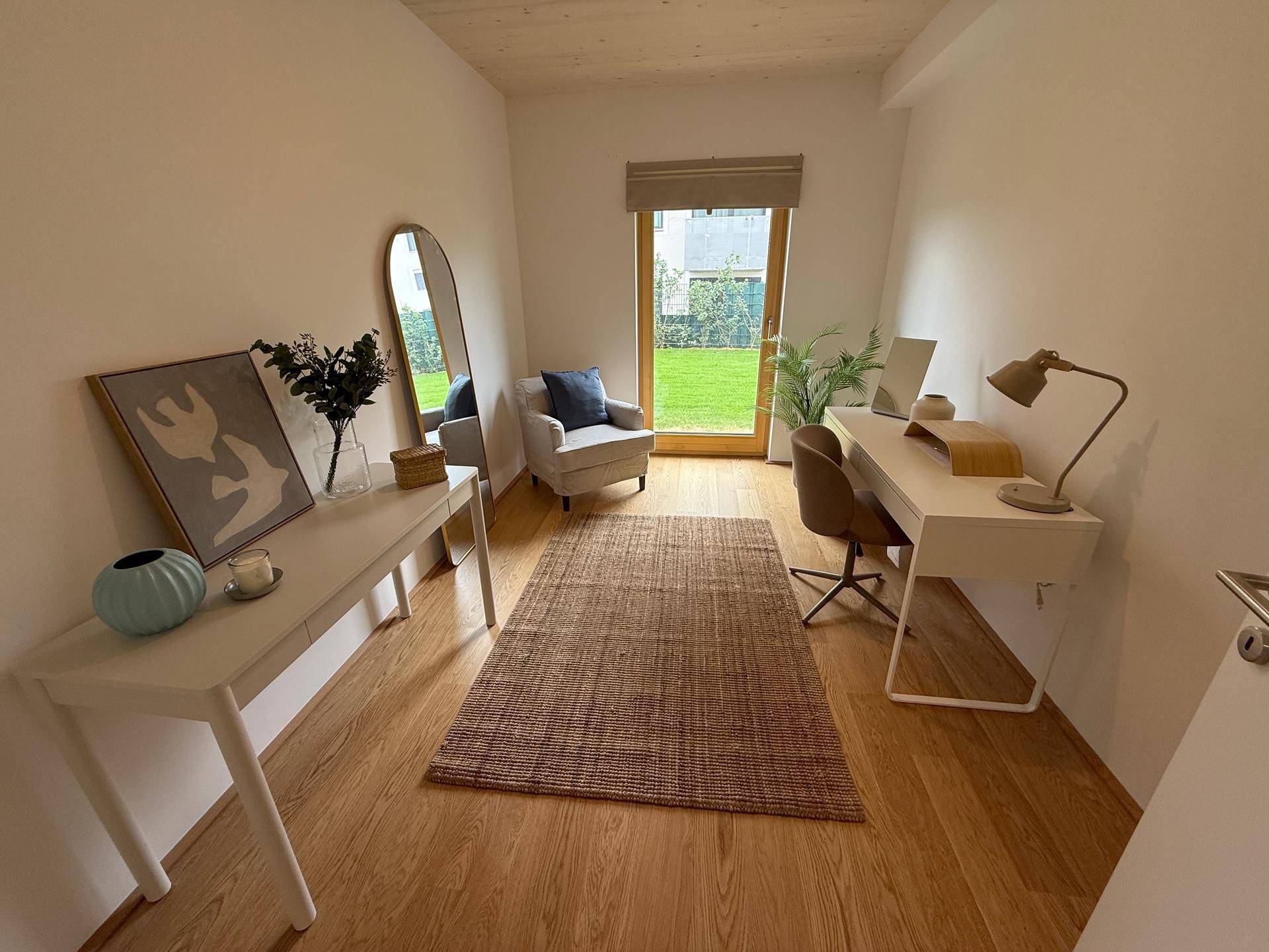 Helles Arbeitszimmer mit Schreibtisch, Holzboden und direktem Zugang zum Gartenbereich.