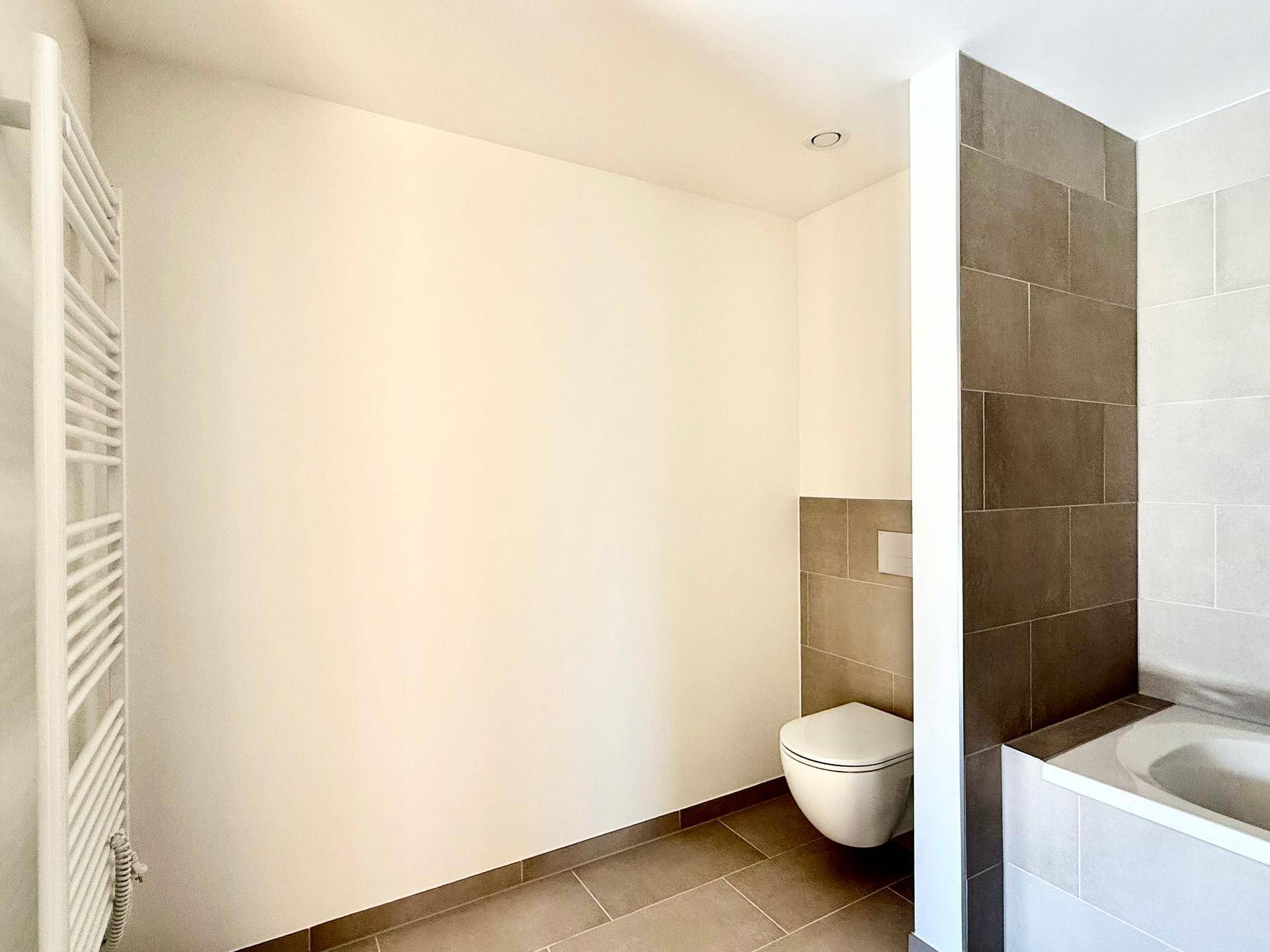 Badezimmer mit Badewanne, wandhängendem WC und Heizkörper, bereit für die Endausstattung.
