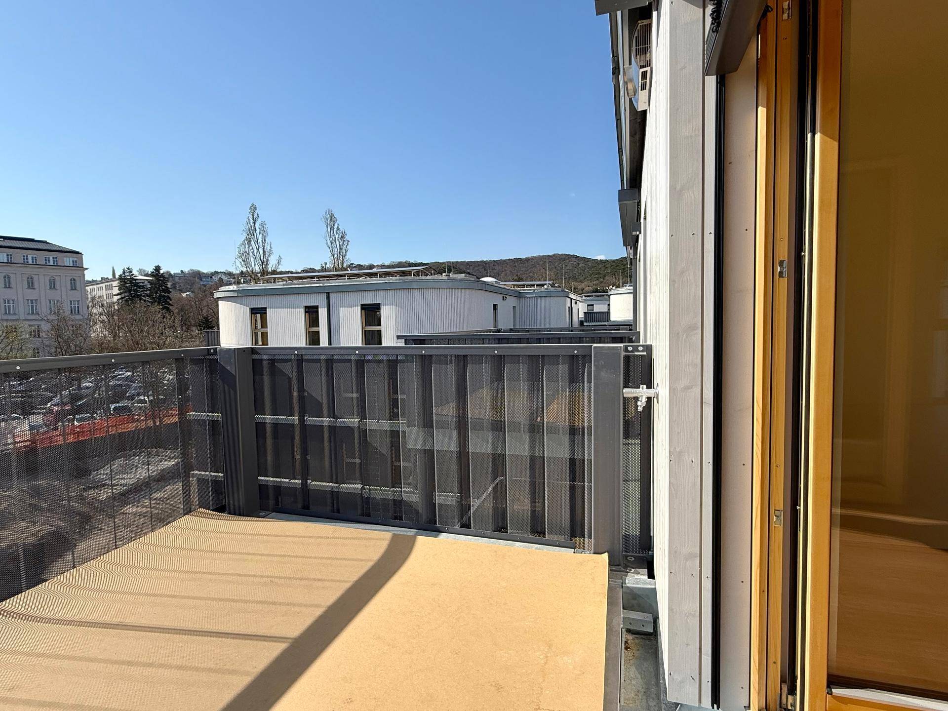 Balkon mit Metallgeländer und Blick auf die umliegende Bebauung unter blauem Himmel.
