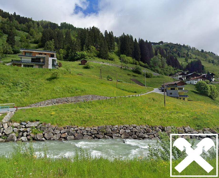 Panoramablick auf einen Fluss, grüne Hügel und Häuser in einer bergigen Landschaft.