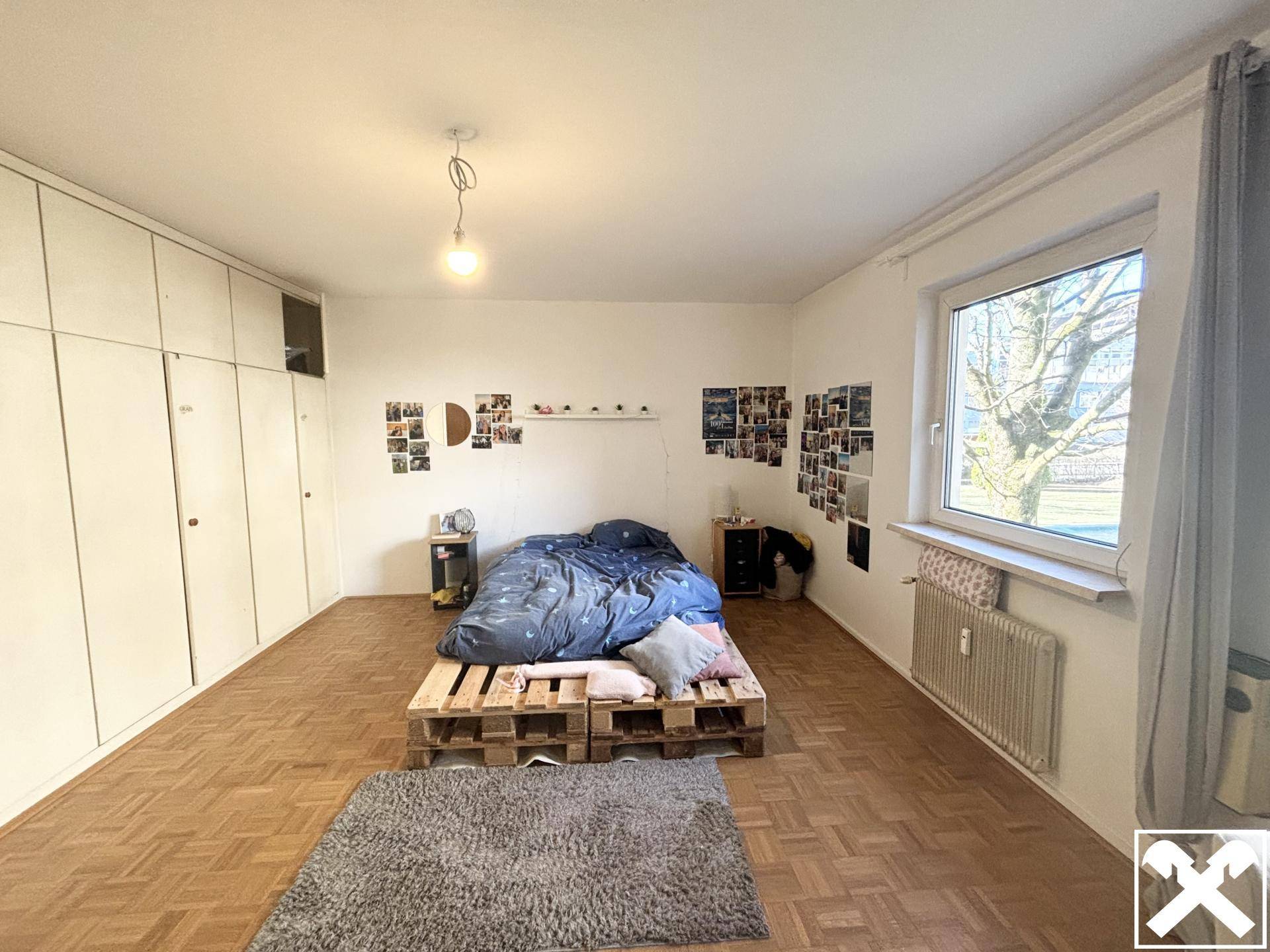 Geräumiges Schlafzimmer mit Einbauschränken, Parkettboden und viel Tageslicht durch große Fenster.