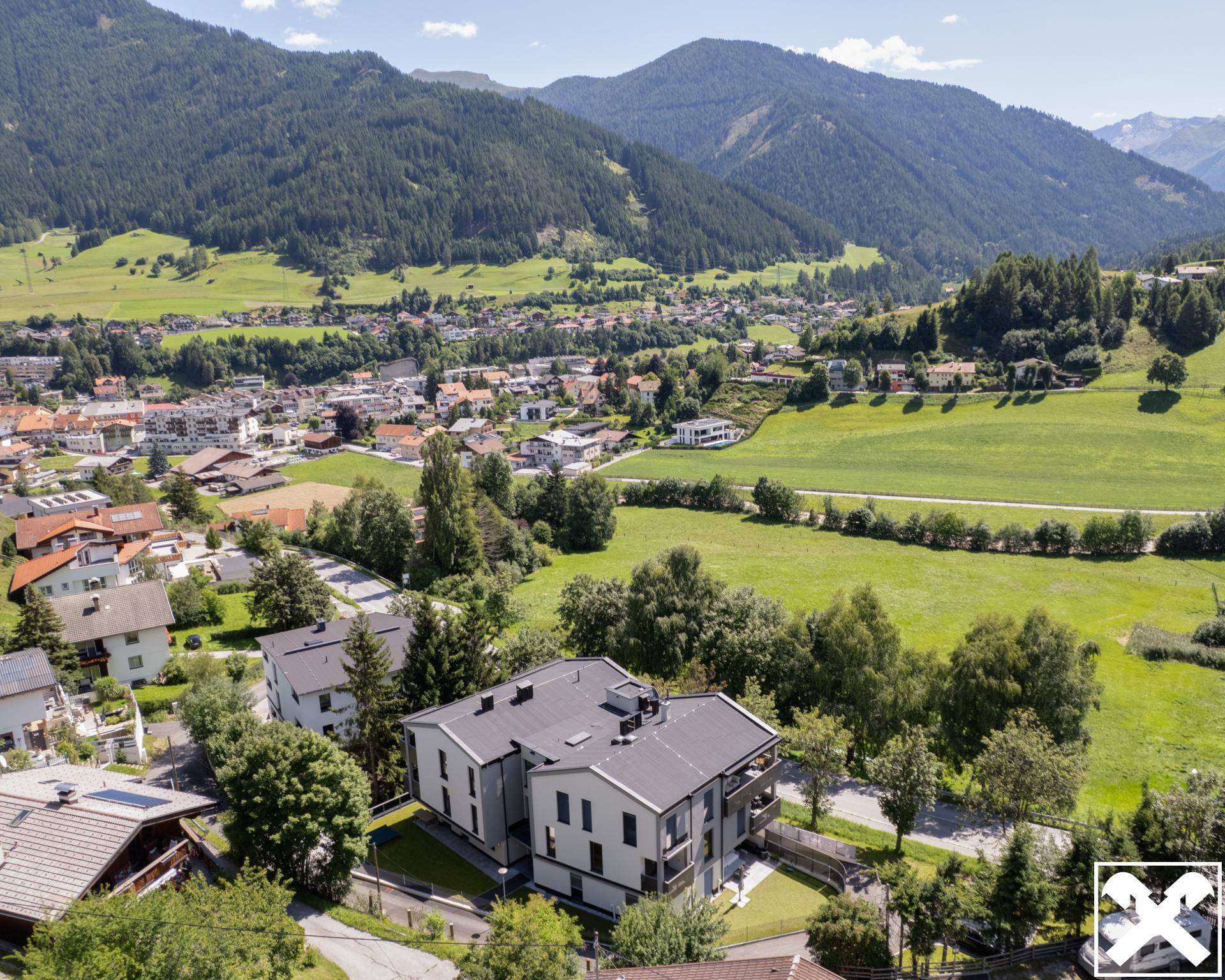 Weitläufige Luftaufnahme des Gebäudes in einer malerischen Bergregion mit Dorfansicht.