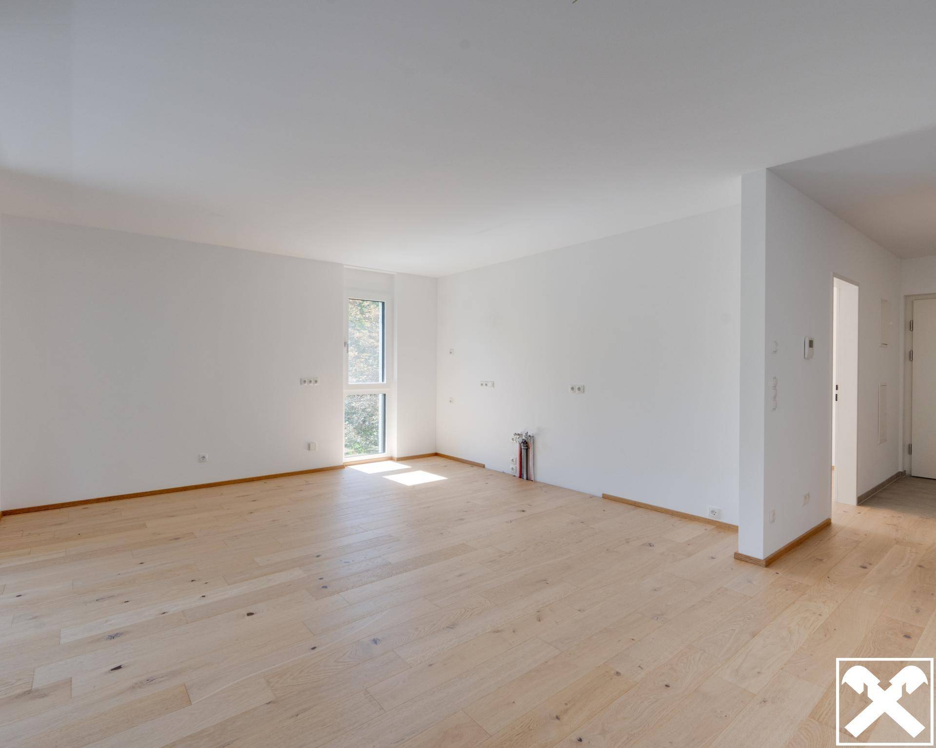 Geräumiger, heller Innenraum mit Holzboden und viel Tageslicht, bereit für individuelle Gestaltung.