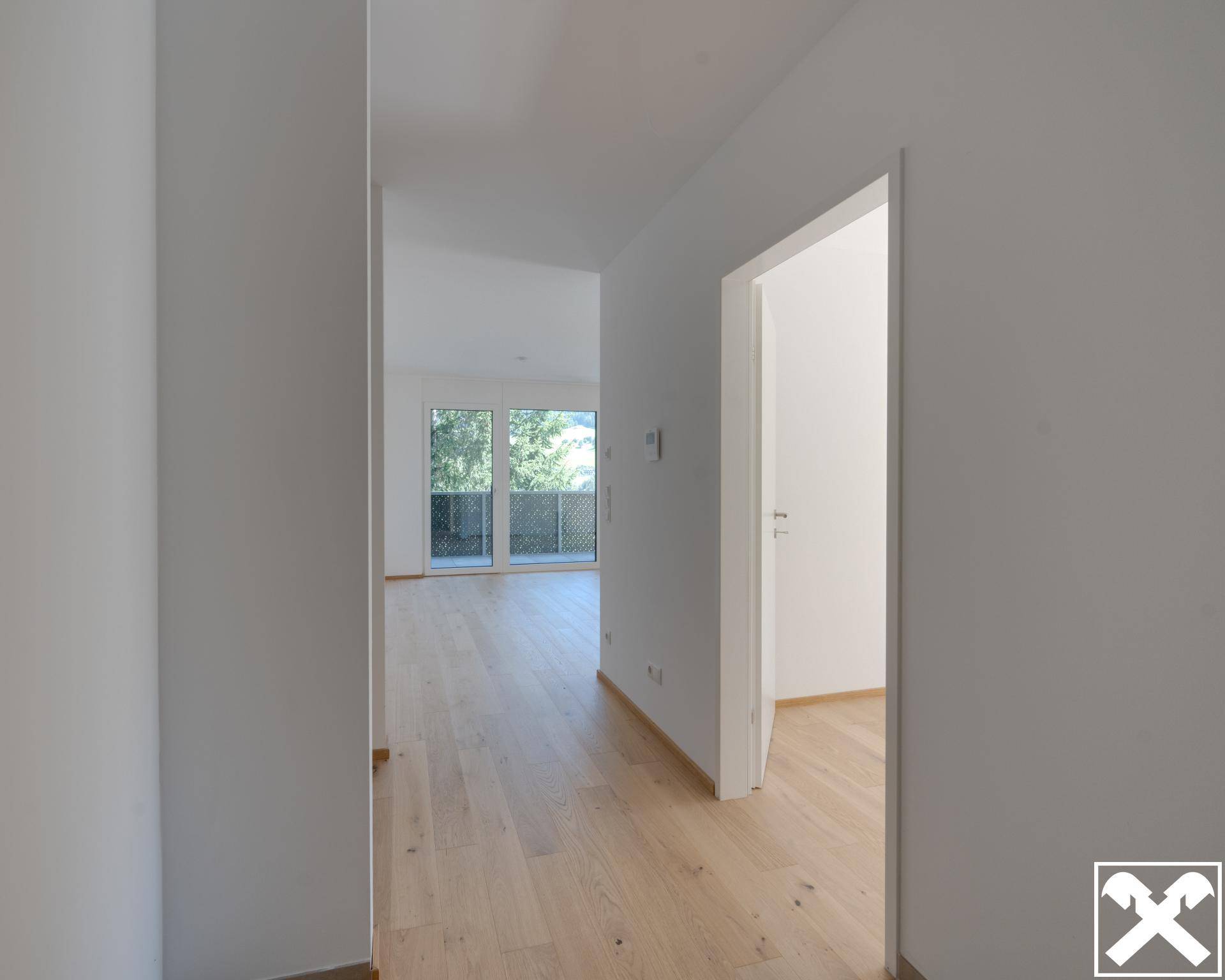 Heller Flur mit Holzboden, der zu den verschiedenen Zimmern der Wohnung führt.