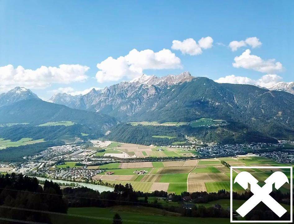 Panoramablick über ein weites Tal mit Stadt, Feldern, Fluss und schneebedeckten Bergen im Hintergrund.