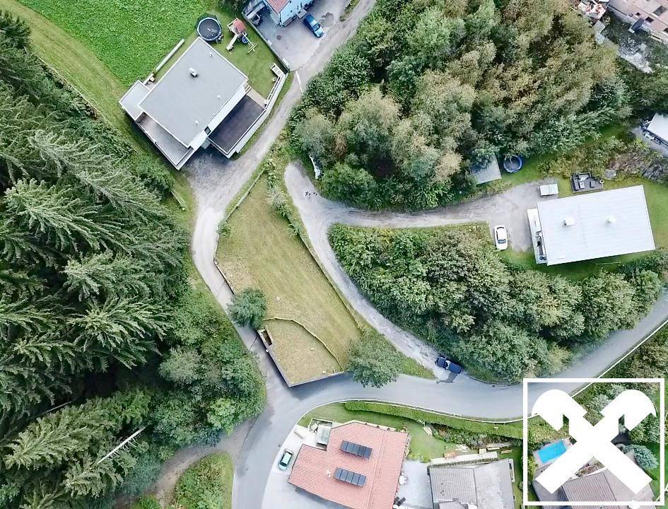 Draufsicht aus der Luft auf das Grundstück mit umliegenden Häusern, Straßen und Waldgebieten.