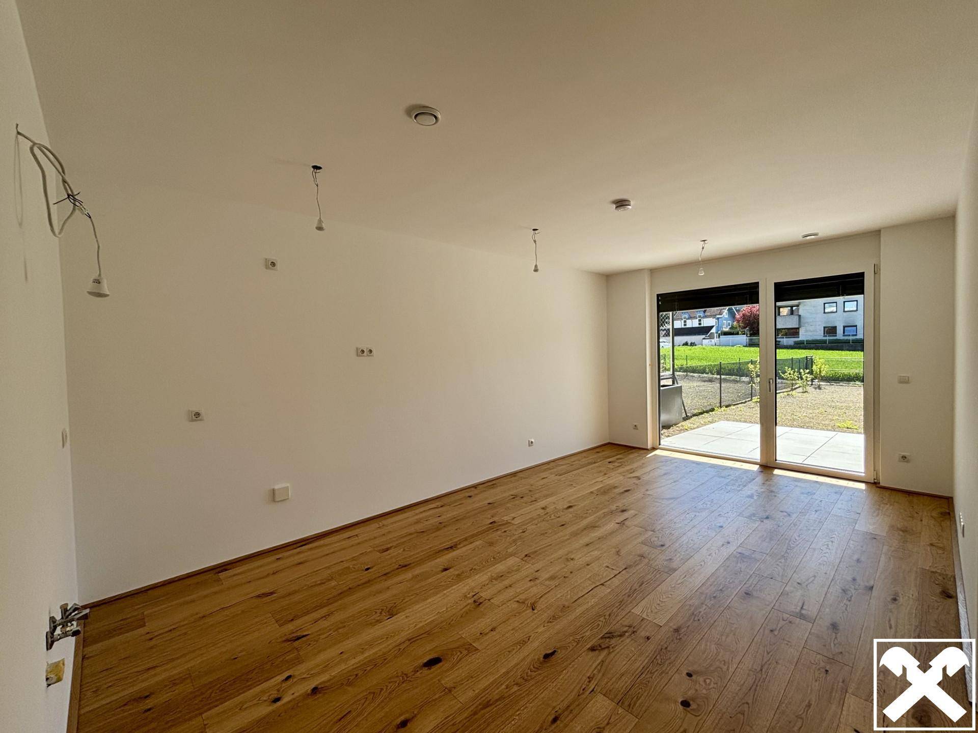 Heller, leerer Raum mit Holzboden und Zugang zur Terrasse, ideal als Wohnzimmer.