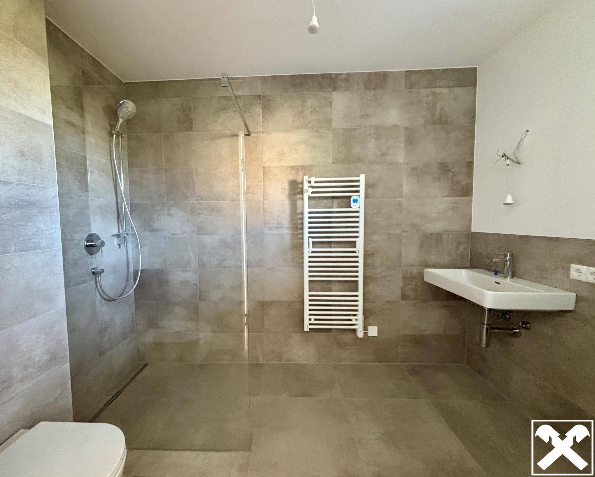 Modernes Badezimmer mit großformatigen Fliesen, ebenerdiger Dusche und Handtuchheizkörper.