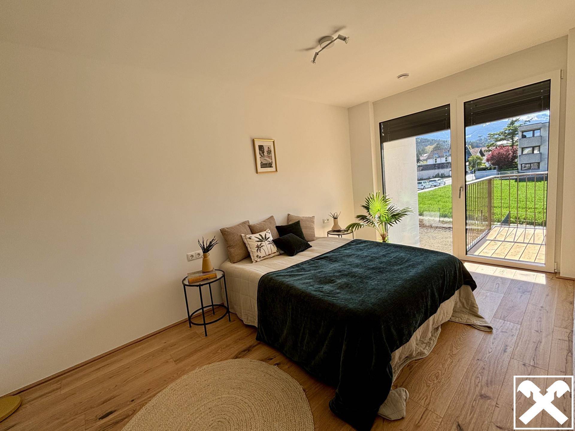 Geräumiges Schlafzimmer mit Holzboden, großen Fenstern und Zugang zu einem Balkon.