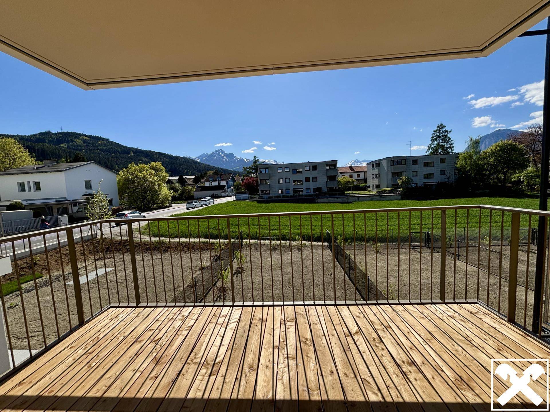 Großer Holzbalkon mit weitem Blick auf die Berge und die grüne Umgebung.