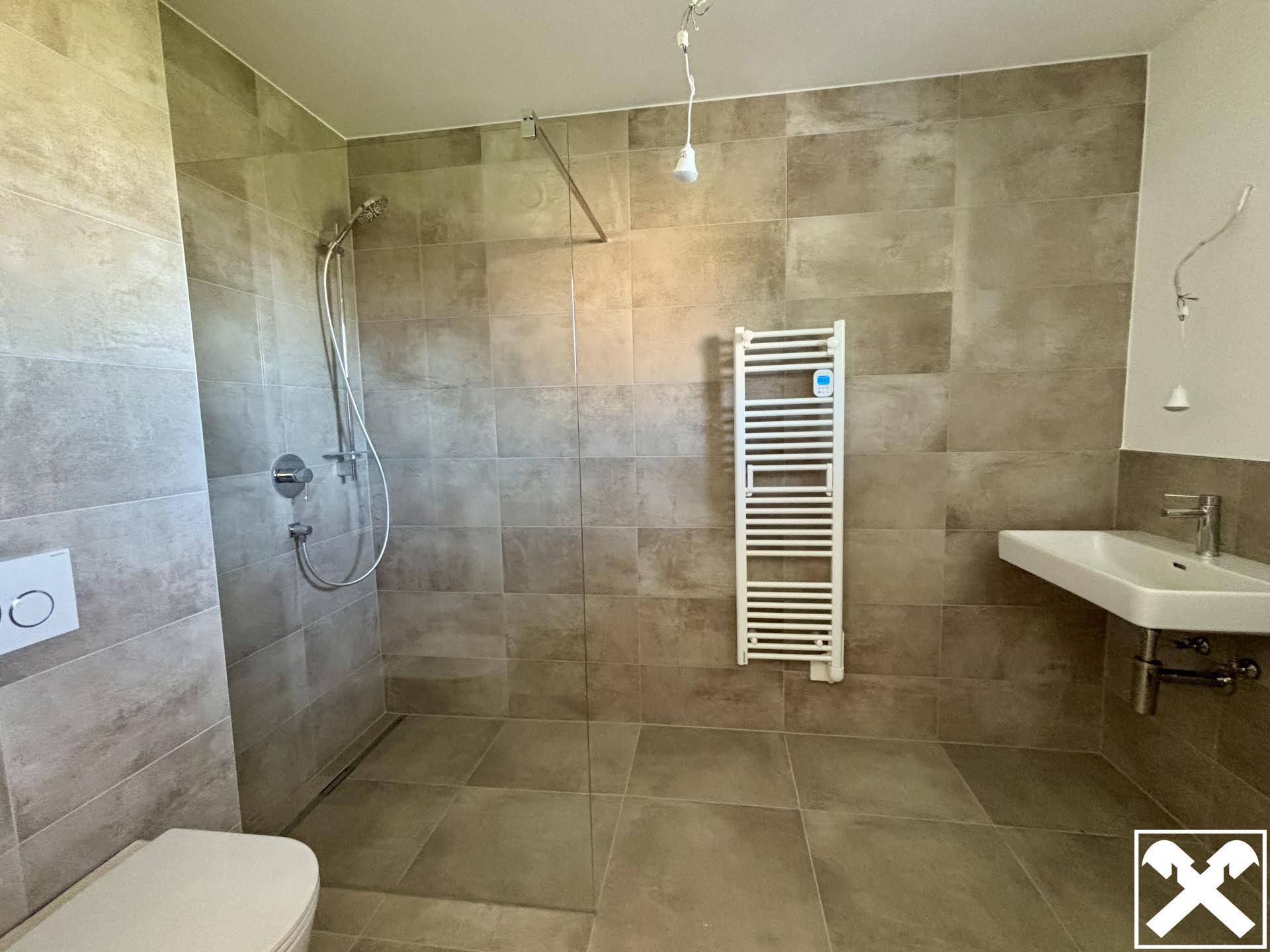 Modernes Badezimmer mit großformatigen Fliesen, ebenerdiger Dusche und Handtuchheizkörper.