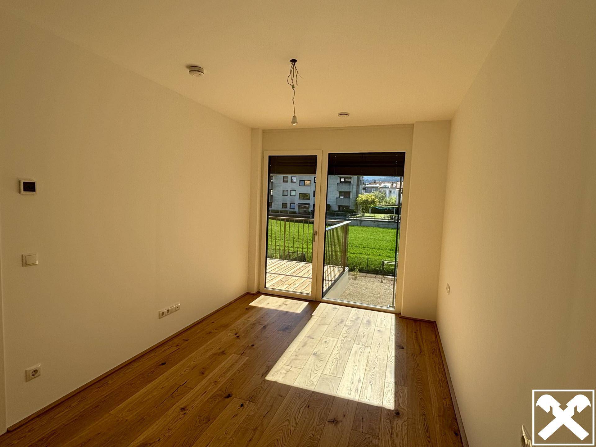 Lichtdurchfluteter Raum mit Eichenparkett und großem Fenster zum Balkon, ideal für Entspannung.