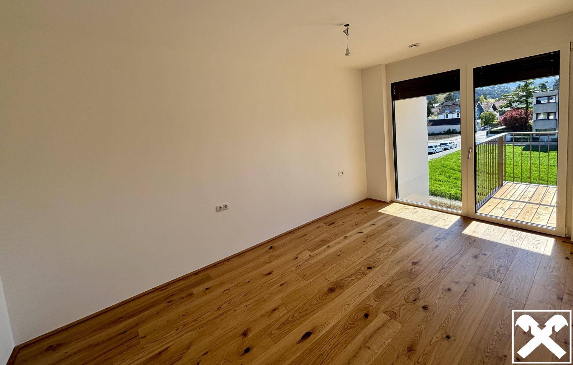 Lichtdurchfluteter Wohnbereich mit Eichenparkett und Zugang zu einem sonnigen Balkon.