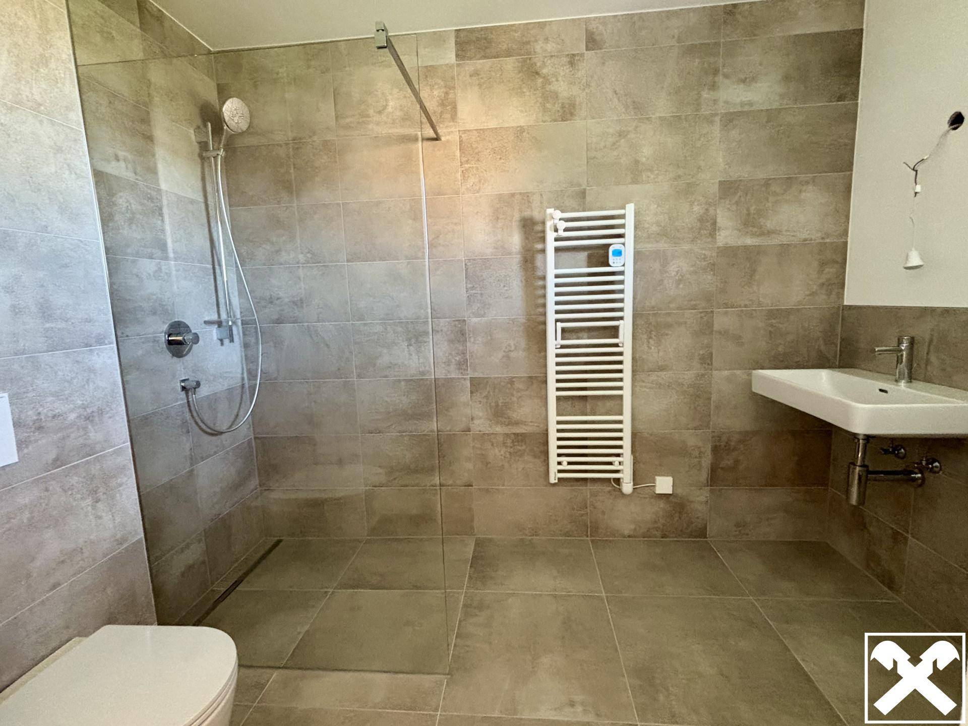 Modernes Badezimmer mit ebenerdiger Dusche, Wand-WC und beheiztem Handtuchhalter.