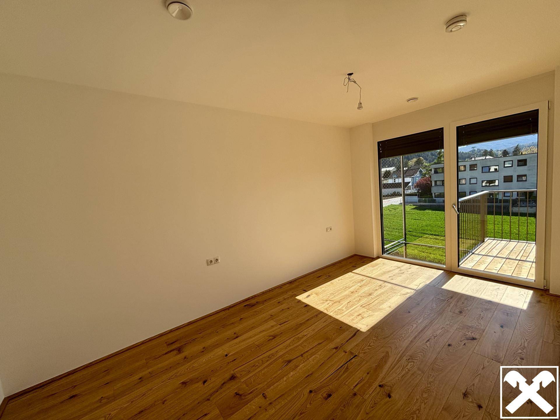 Heller Raum mit Holzboden und Zugang zu einem Balkon, ideal als Wohn- oder Schlafzimmer.