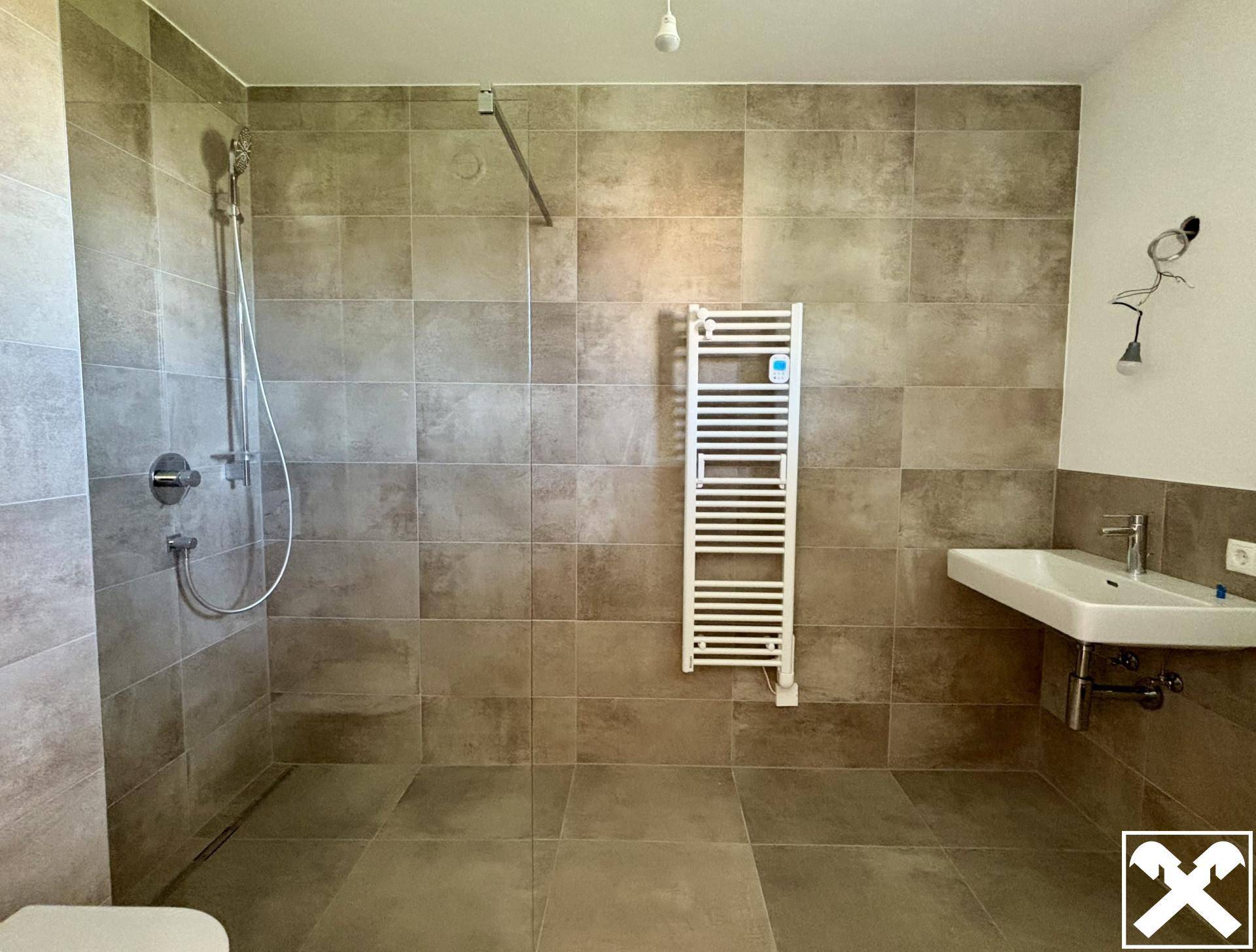 Modernes Badezimmer mit ebenerdiger Dusche, Fliesenboden und Handtuchheizkörper.