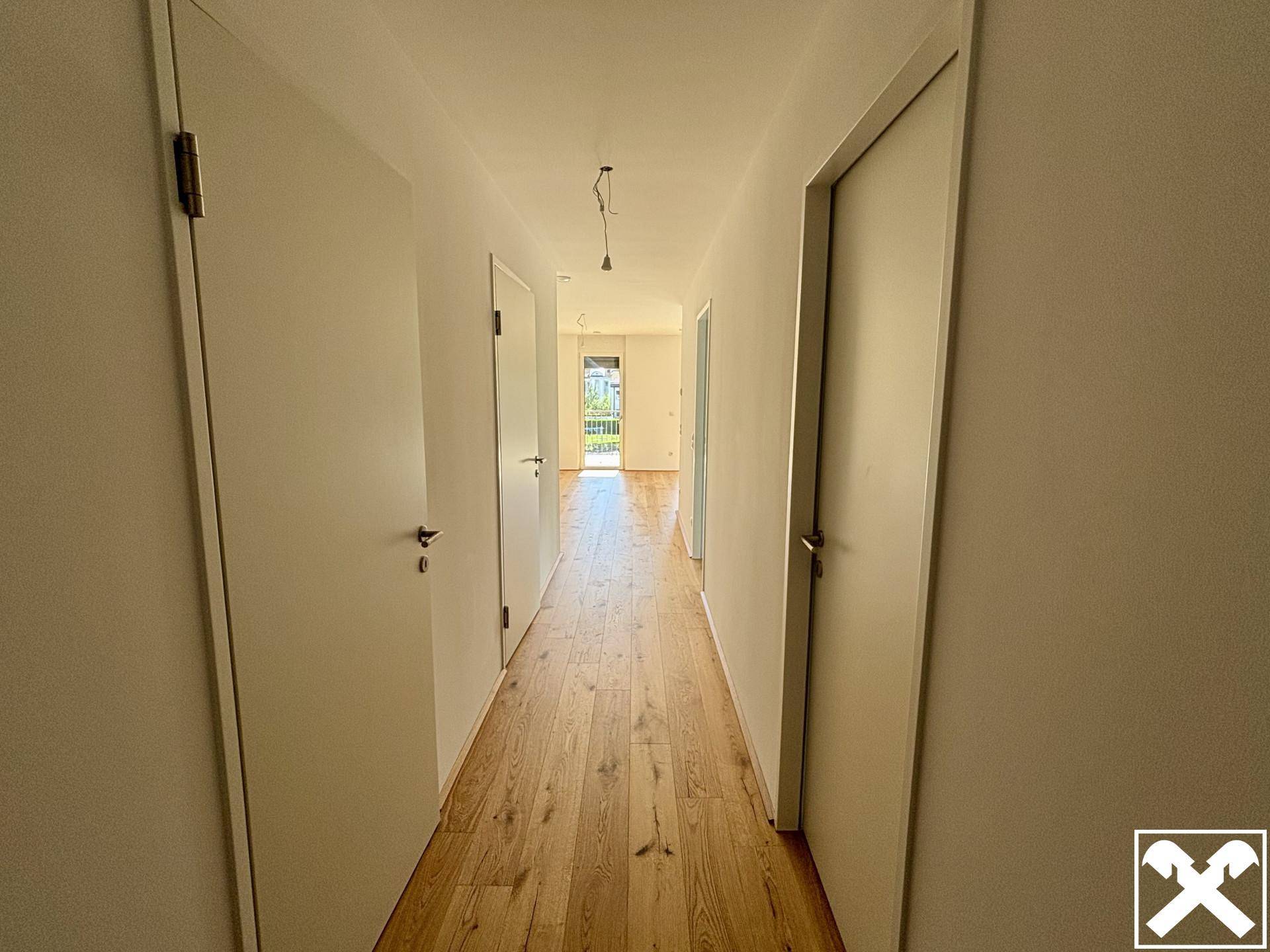 Langer, heller Flur mit Holzparkettboden und mehreren Türen, der zu weiteren Räumen führt.
