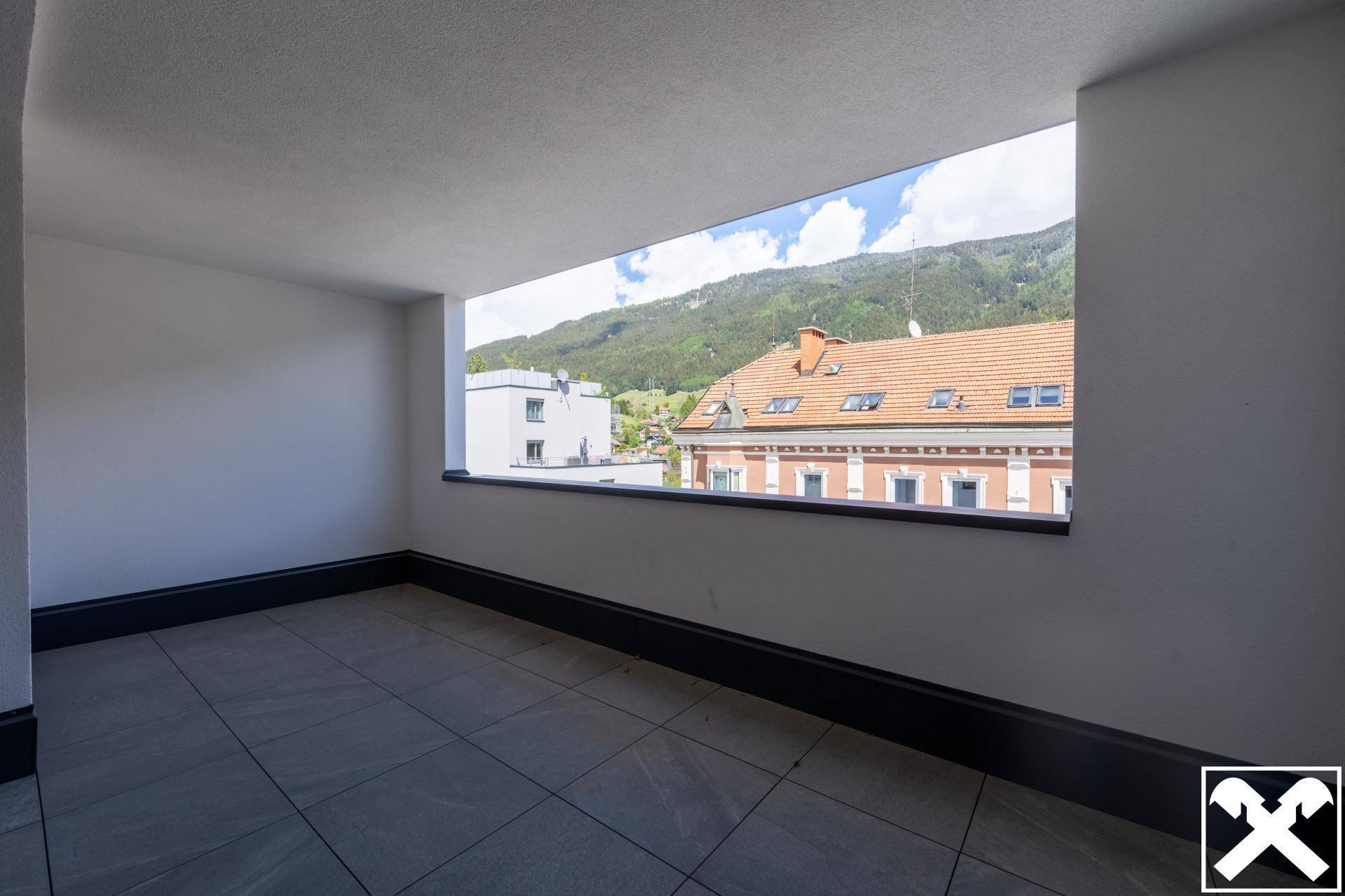 Überdachter Balkon mit Fliesenboden und weitem Blick auf die Berge.