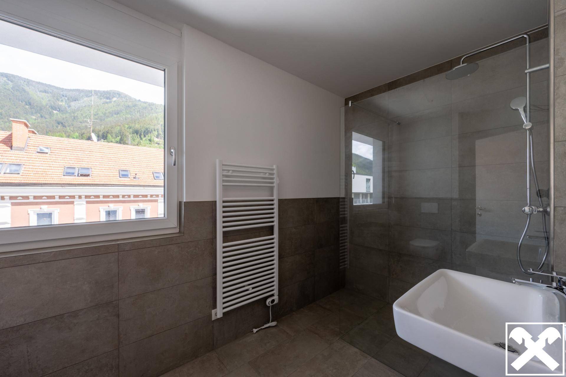 Modernes Badezimmer mit begehbarer Dusche, Fliesen und beheiztem Handtuchhalter.