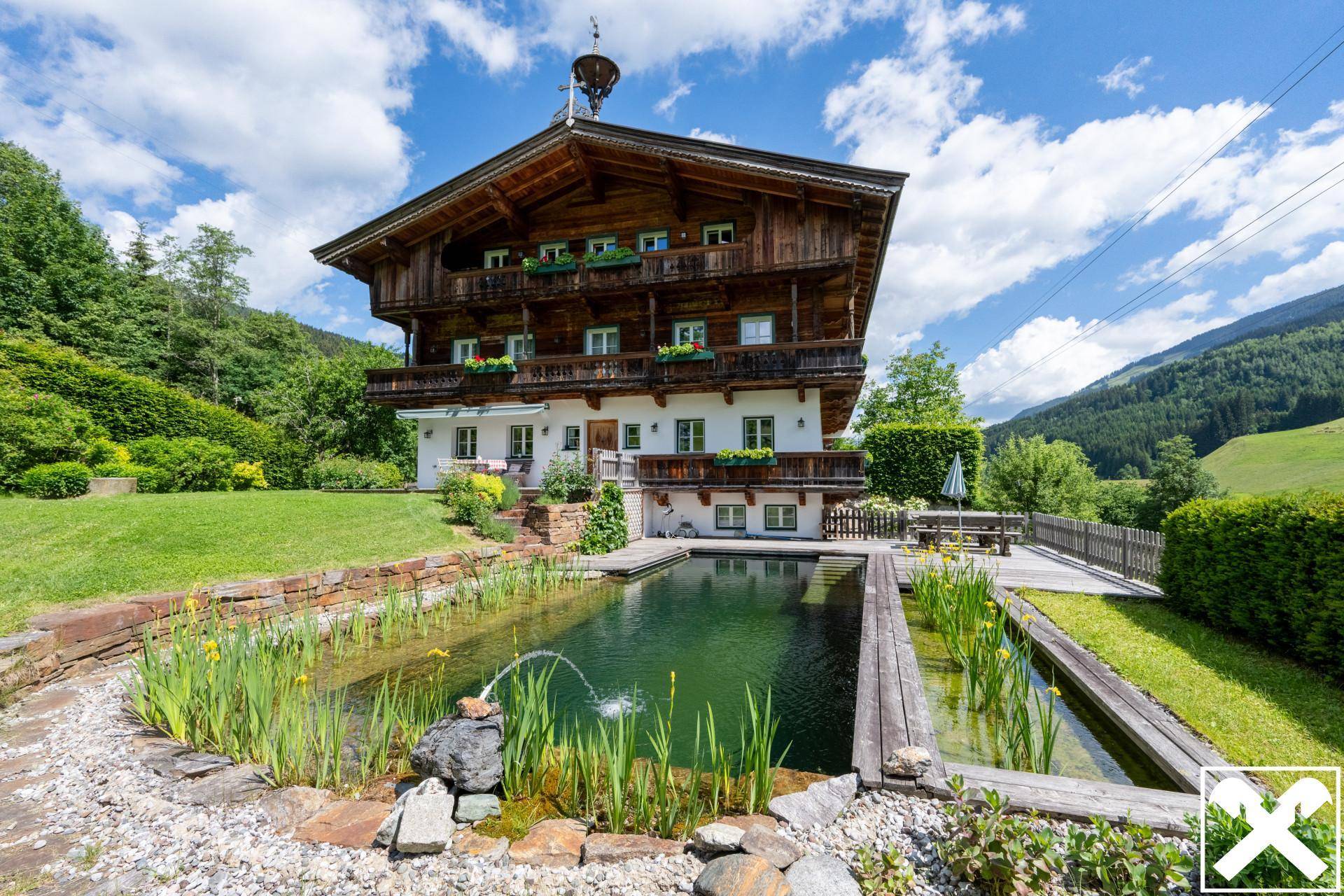Traditionelles Chalet mit Naturpool und gepflegtem Garten in sonniger alpiner Umgebung.