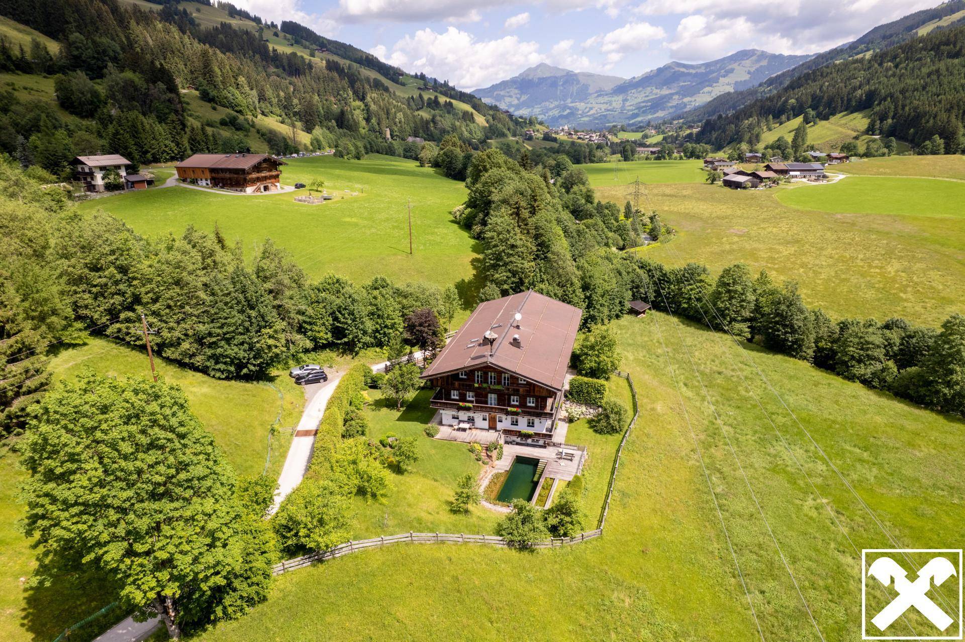 Weitläufiges Anwesen mit Chalet, Pool und Zufahrt, eingebettet in ein grünes Alpentals.