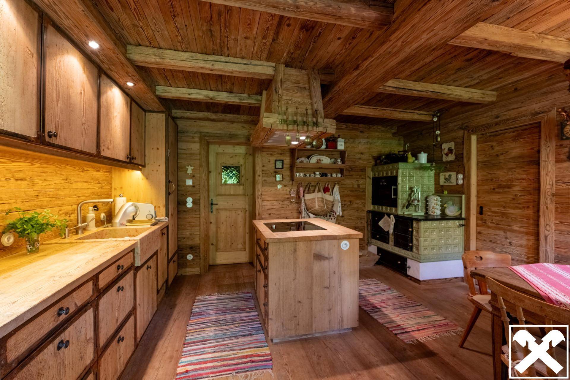 Rustikale Holzküche mit traditionellem Kachelofen, Kücheninsel und gemütlicher Atmosphäre.