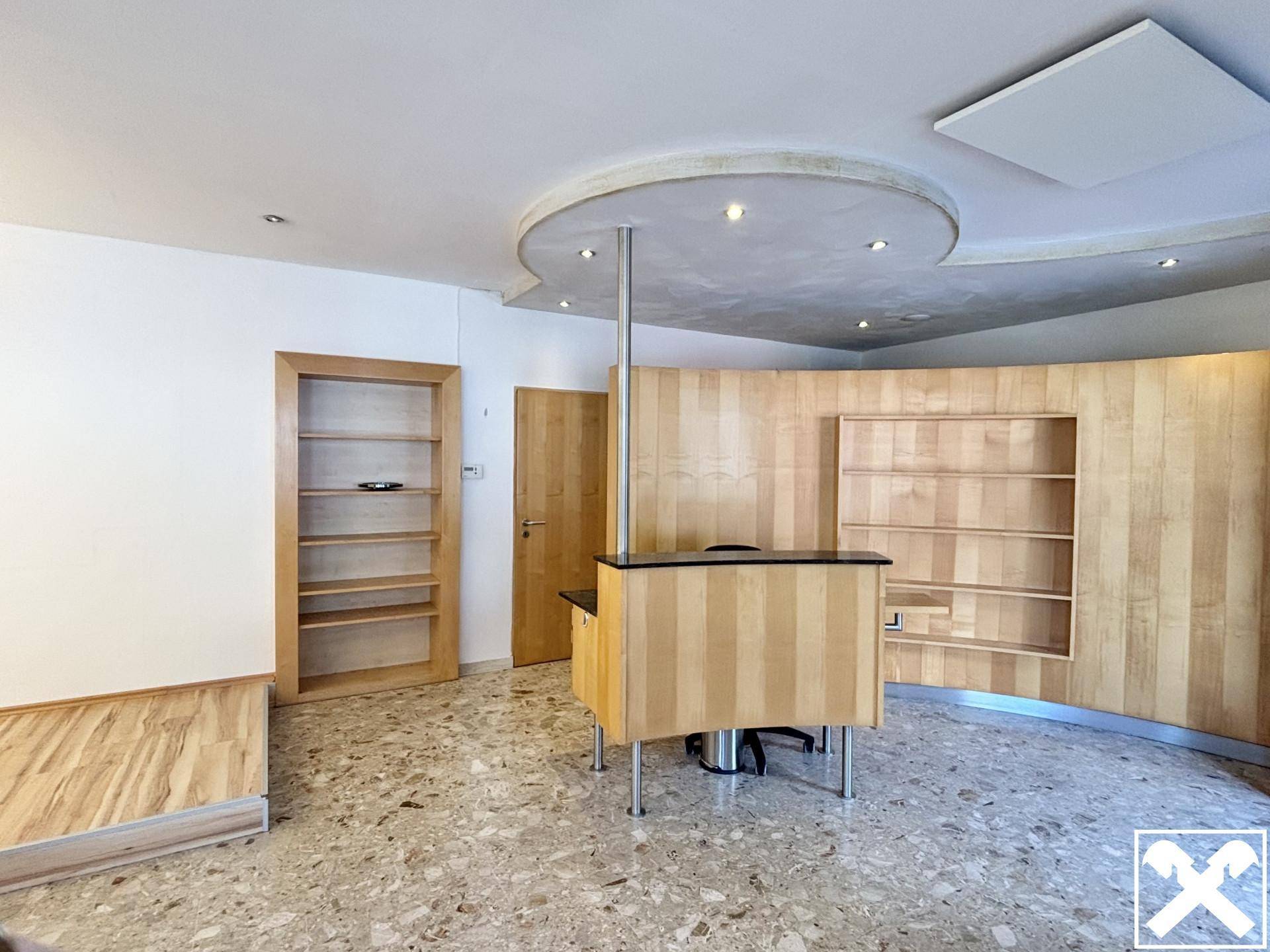 Empfangsbereich mit geschwungener Decke, Holzvertäfelung und integrierten Regalen.