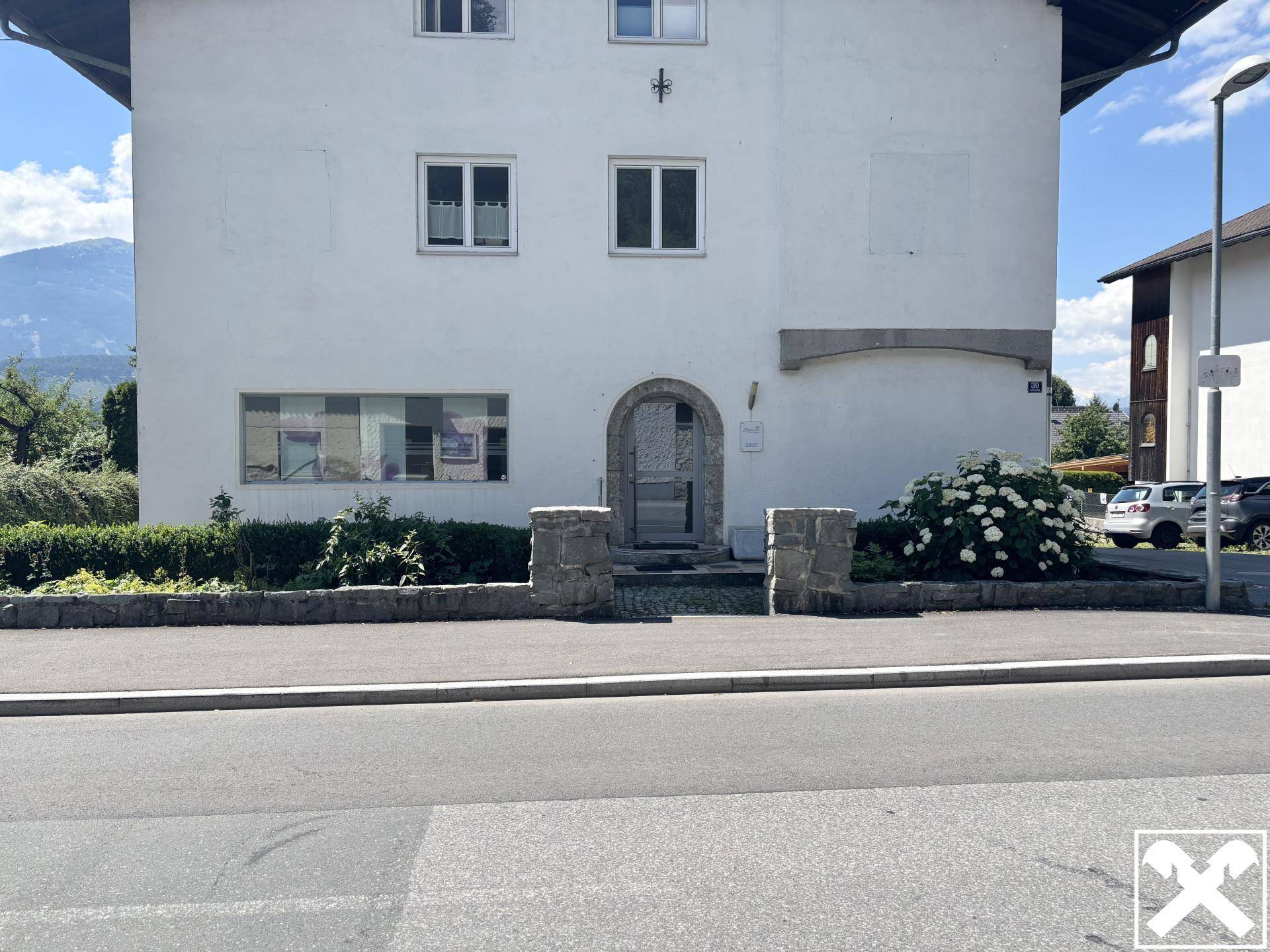 Weißes Wohnhaus mit traditioneller Architektur und gepflegtem Vorgarten.