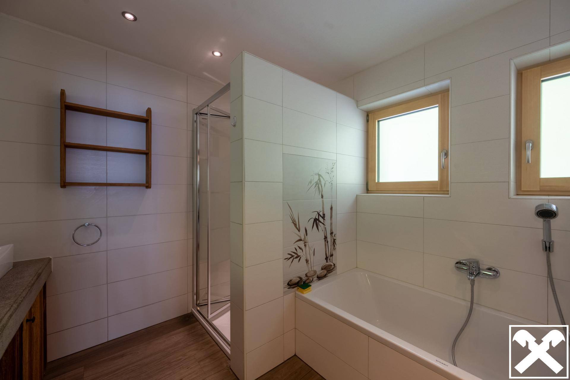 Helles Badezimmer mit Badewanne, Duschkabine und Fenster für natürliche Belüftung.