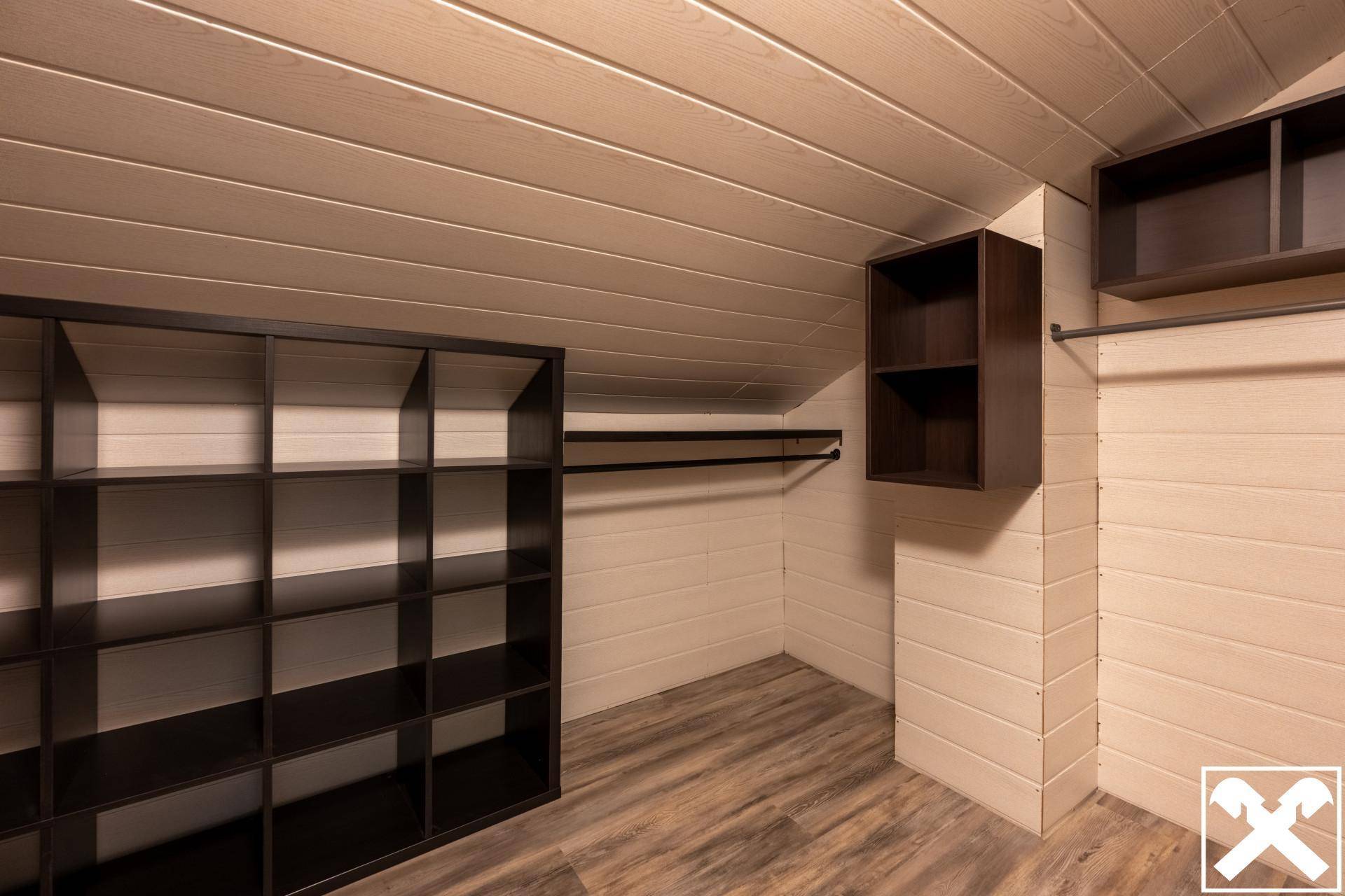 Begehbarer Kleiderschrank mit Regalsystemen und Holzverkleidung an Wänden und Decke.