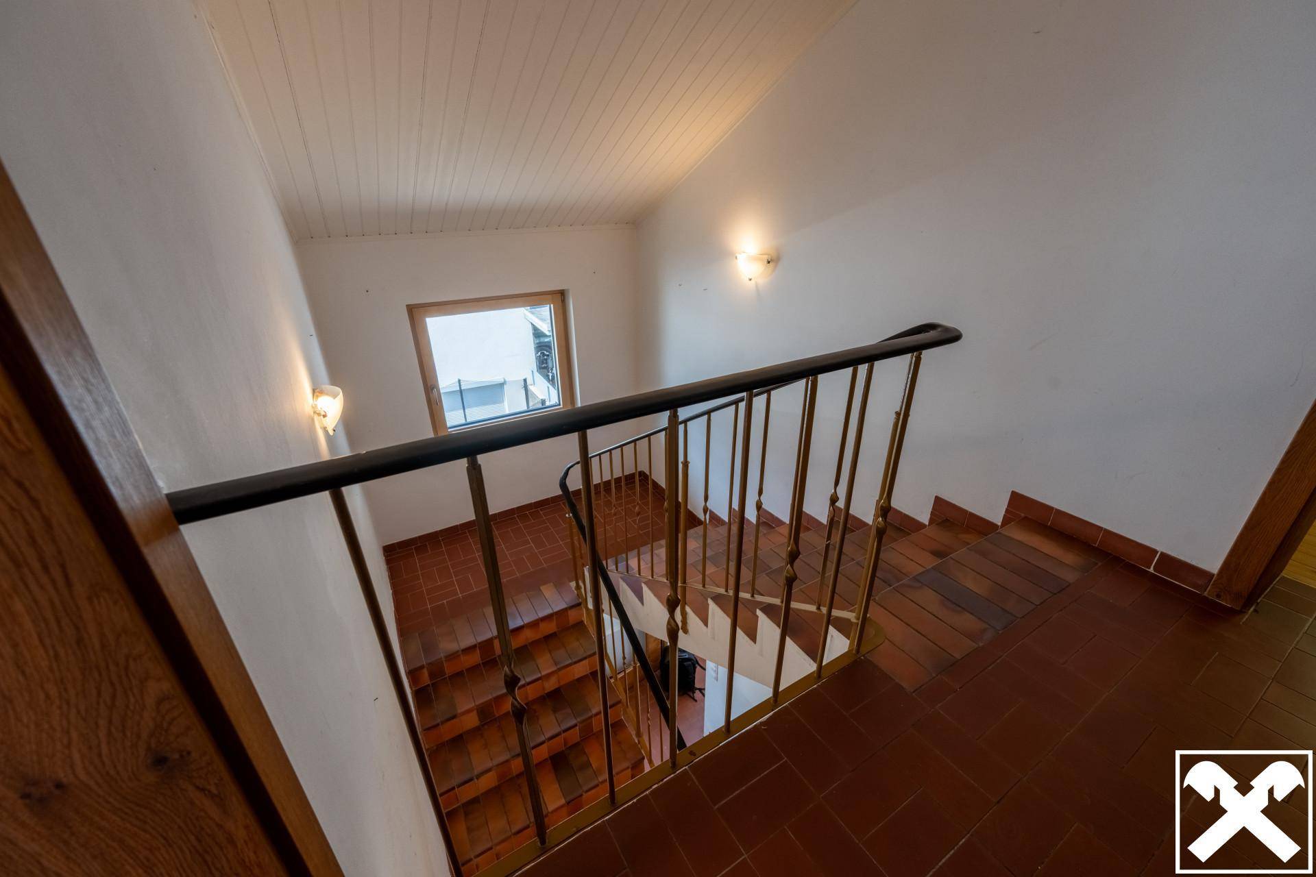 Blick von oben auf das Treppenhaus mit Fliesenstufen und Fenster für Helligkeit.