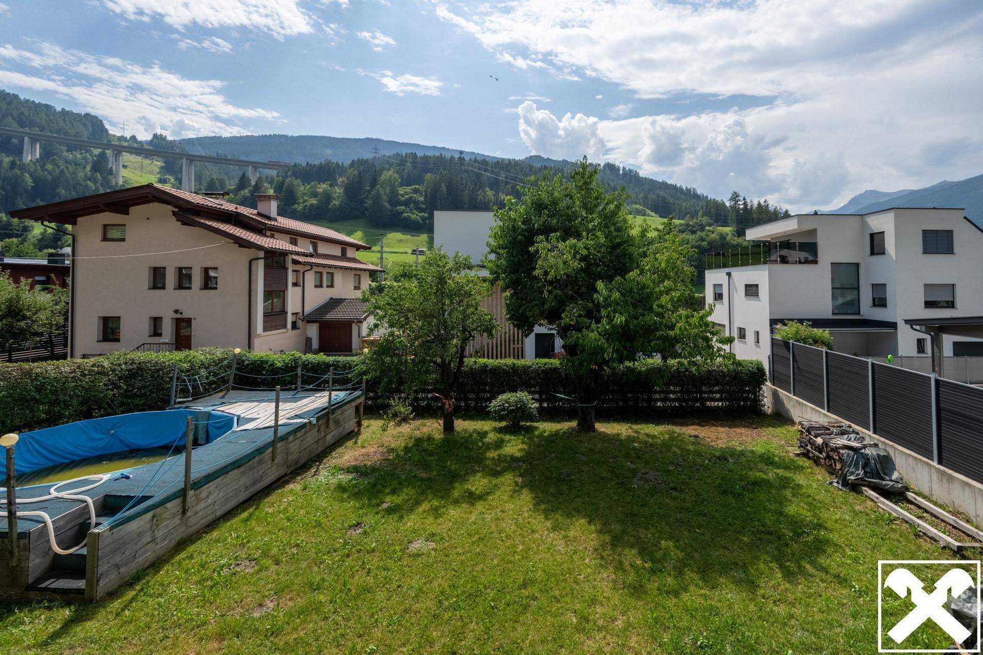Großer Garten mit Rasenfläche, Aufstellpool und weitem Blick auf die Berge.