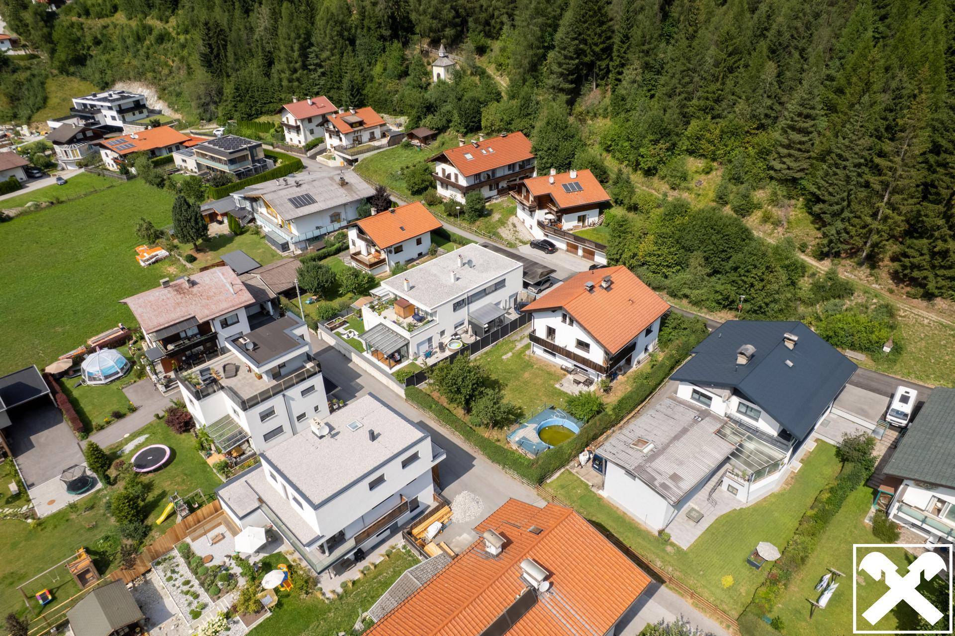 Weitläufige Luftaufnahme einer Wohngegend, eingebettet in eine grüne Berglandschaft.
