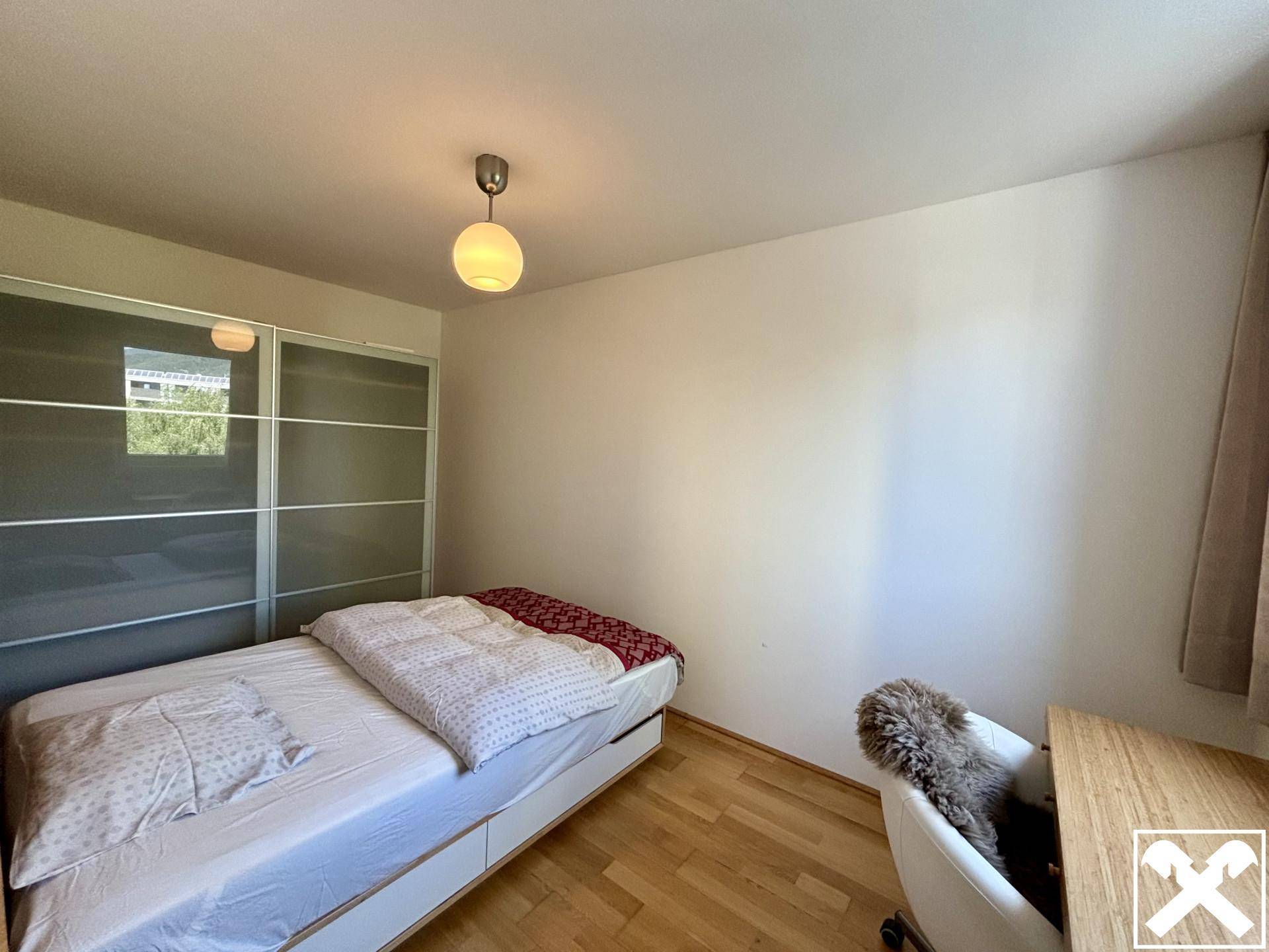 Helles Schlafzimmer mit Einzelbett, Schreibtisch und modernem Schiebetürenschrank, bietet viel Stauraum.