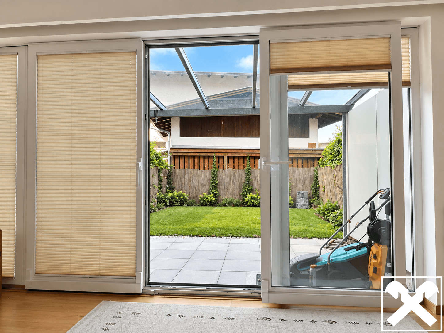 Große Glasschiebetür öffnet sich zu einer Terrasse und einem gepflegten Gartenbereich.
