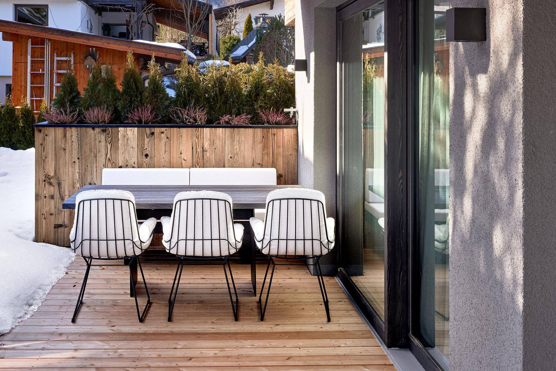 Gemütliche Holzterrasse mit modernen Gartenmöbeln und Blick auf die Umgebung.
