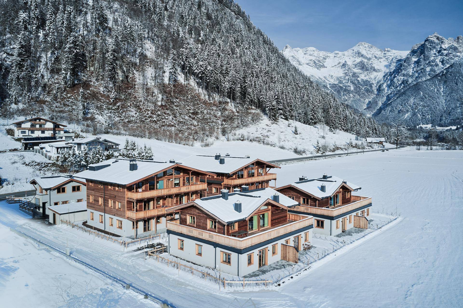 Eine Gruppe von Neubauten im alpinen Stil mit Blick auf die majestätische Bergwelt.
