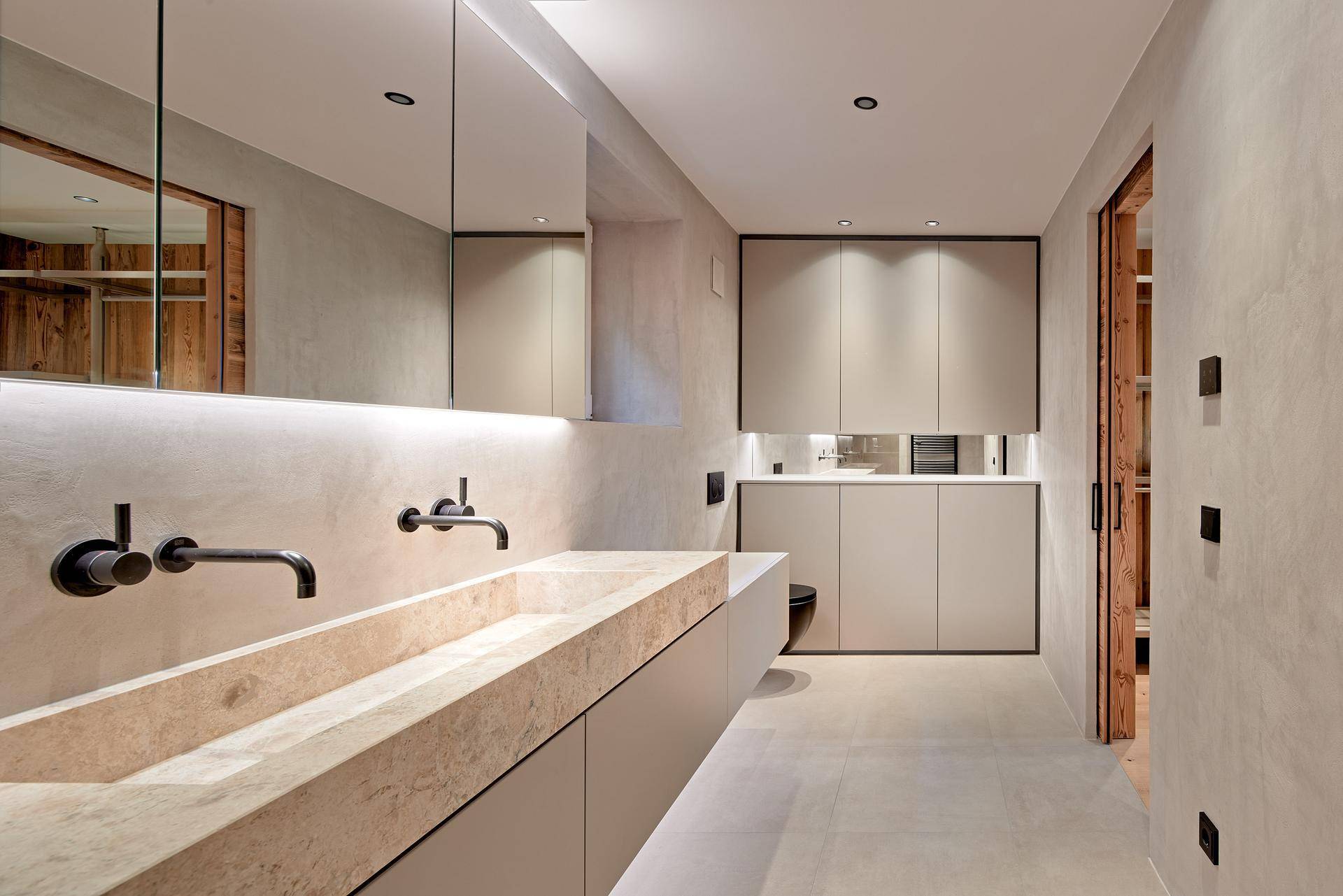 Modernes Badezimmer mit Doppelwaschbecken, integrierten Schränken und Wand-WC.