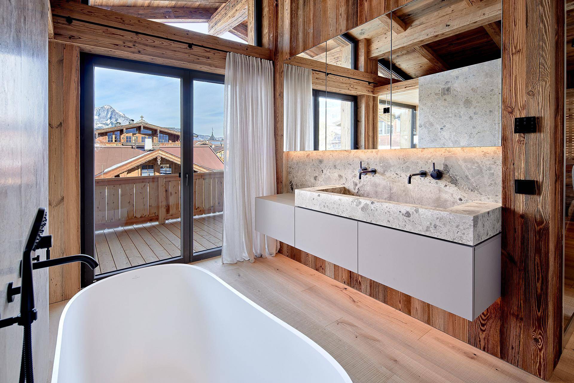 Modernes Badezimmer mit Doppelwaschbecken, freistehender Badewanne und Bergblick.