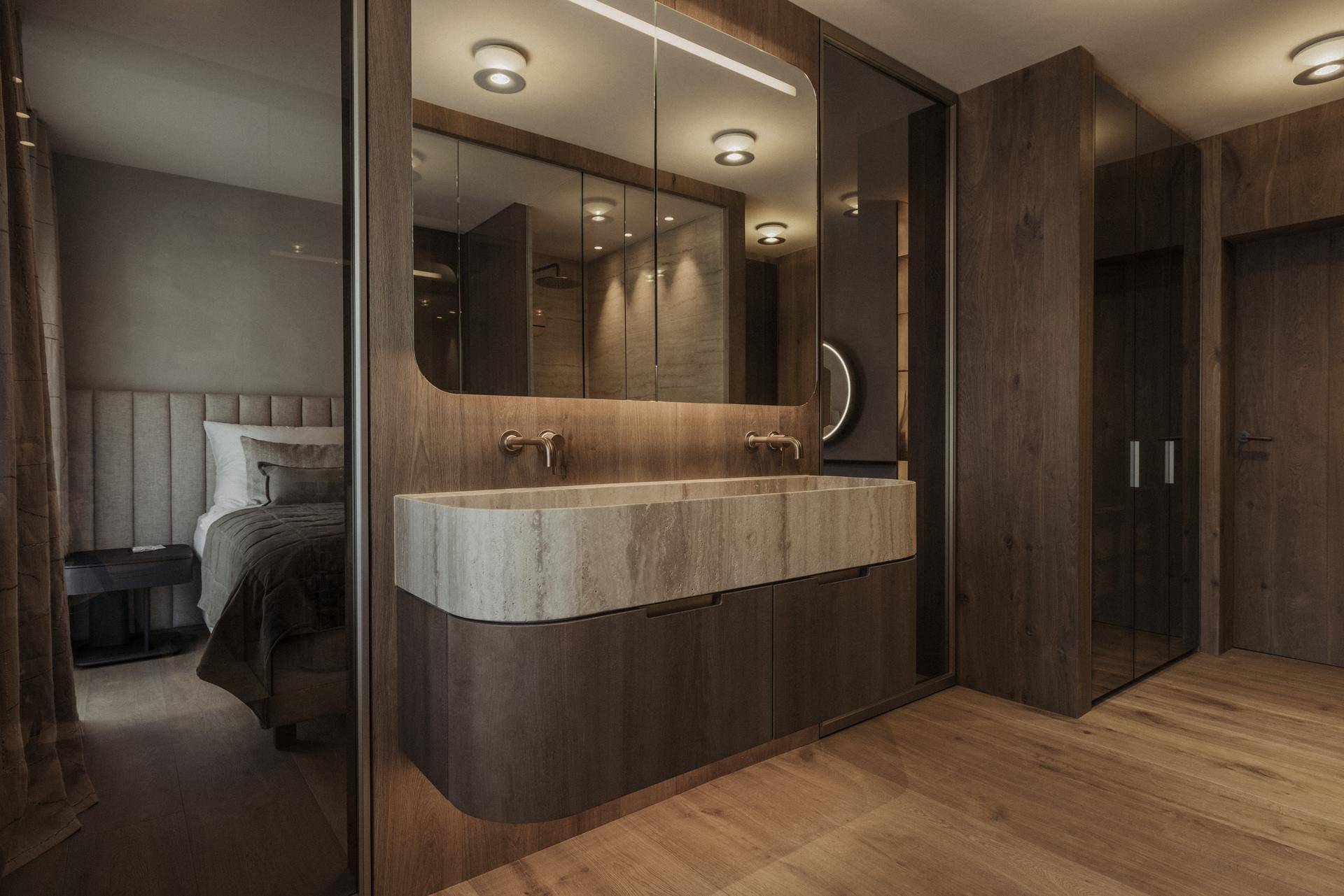 Luxuriöses Badezimmer mit Doppelwaschbecken aus Stein und direktem Zugang zum Schlafzimmer.