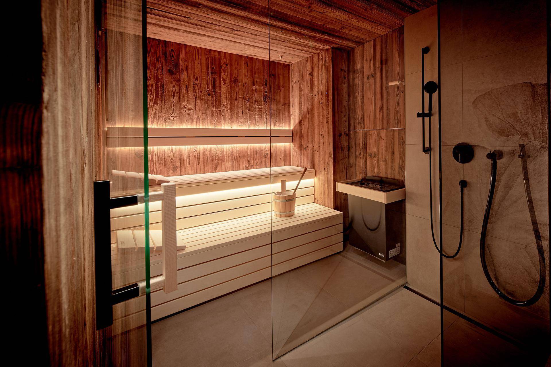 Moderne Holzsauna mit integrierter Beleuchtung und angrenzender Dusche.
