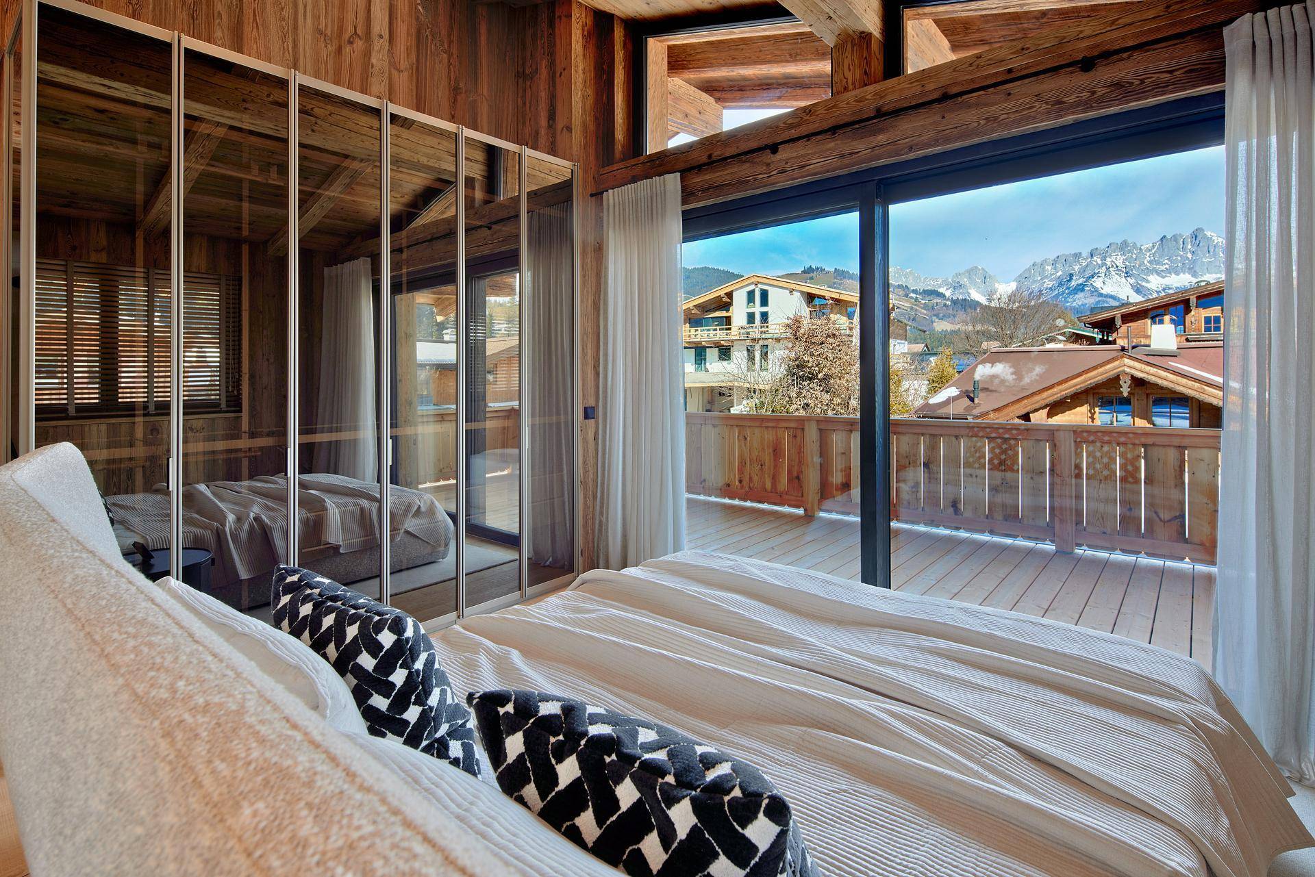 Schlafzimmer mit großen Fenstern, Bergblick und Zugang zu einer Terrasse.