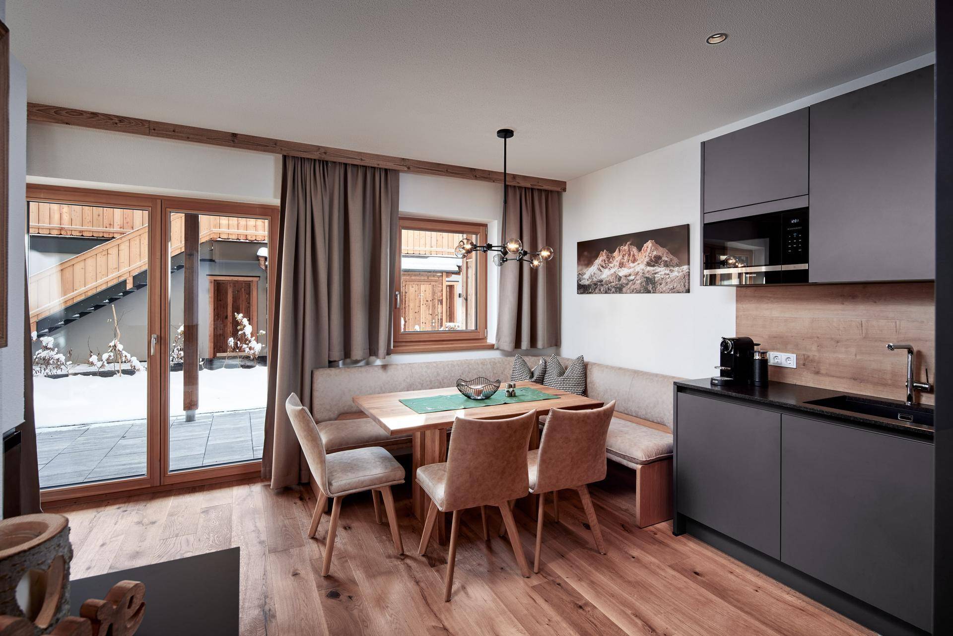 Heller Essbereich mit Holztisch und Sitzbank, angrenzend an eine moderne Küche mit Zugang nach draußen.
