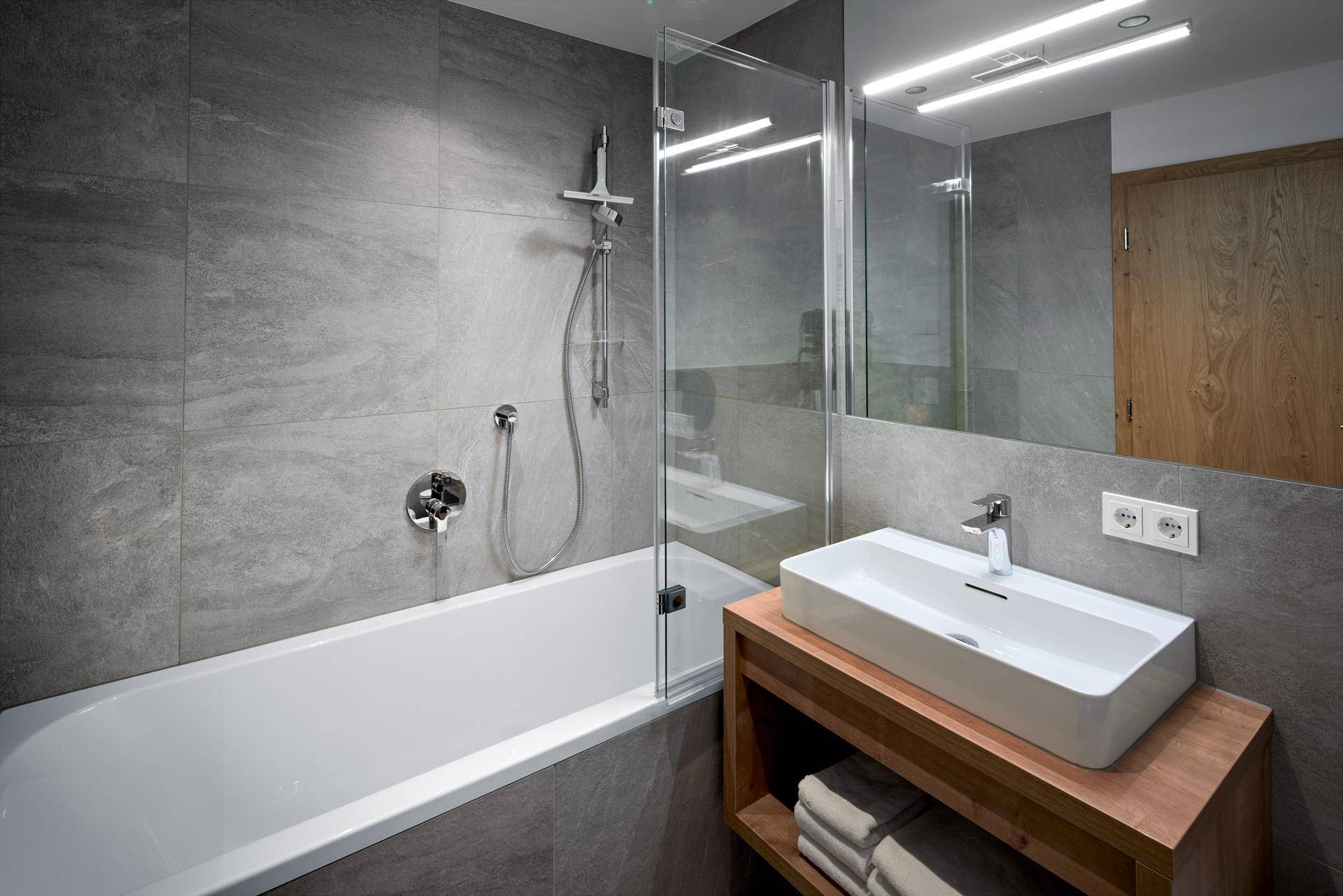 Modernes Badezimmer mit Badewanne, Duschfunktion und stilvollem Einzelwaschbecken.