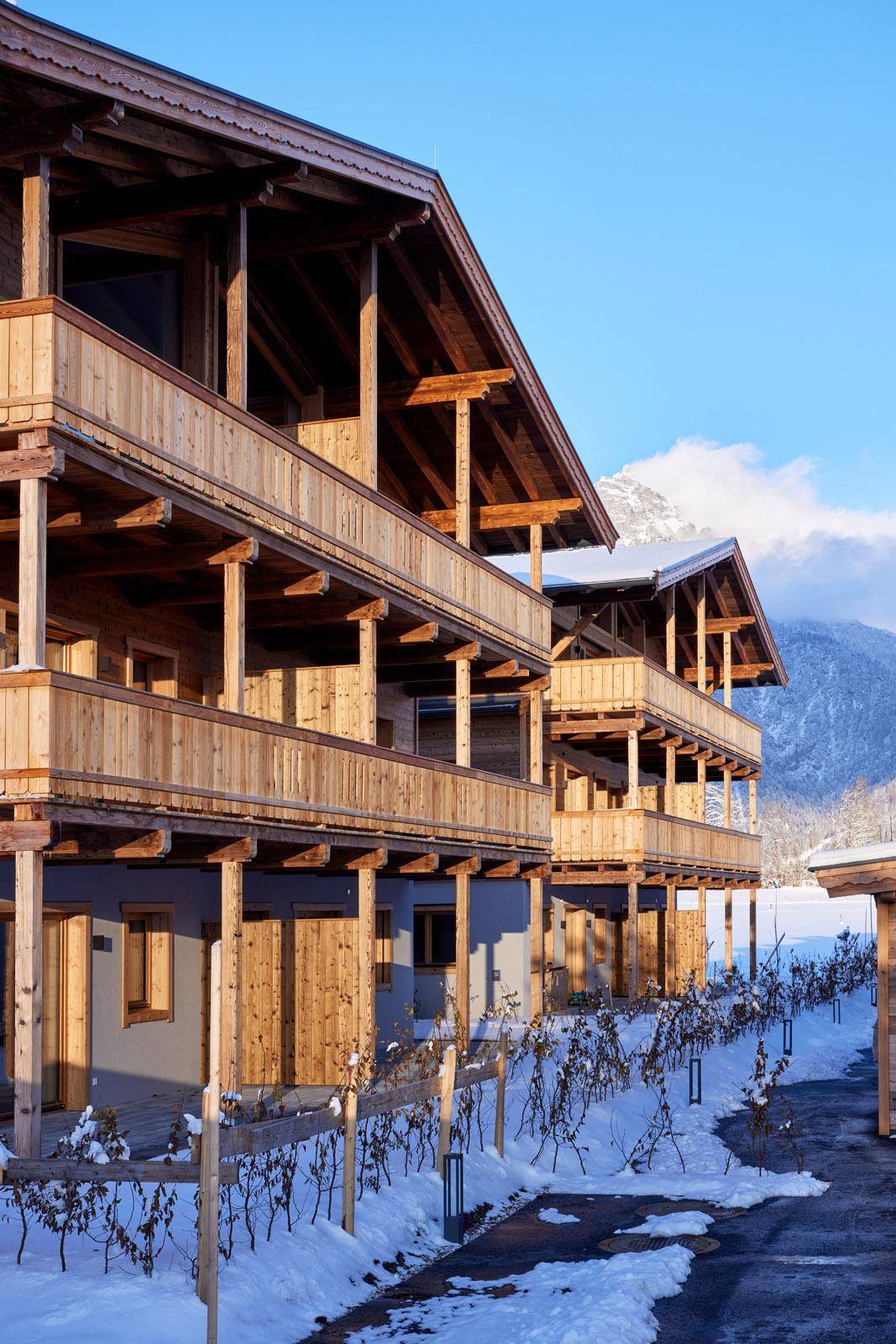 Attraktive Holzfassade mit Balkonen und schneebedeckter Umgebung vor einer Bergkulisse.